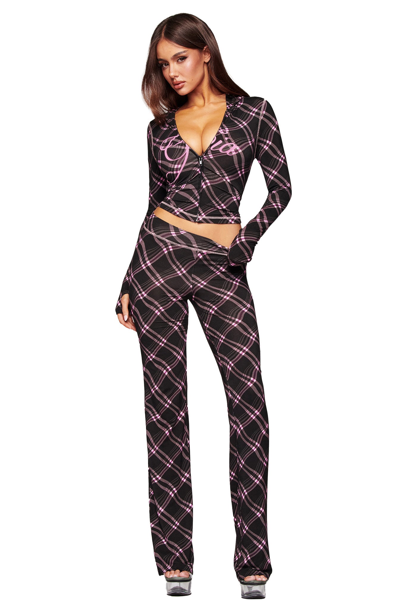 A woman models the I.AM.GIA BLARE TRACKPANT in Black Warped Plaid, paired with a coordinating long-sleeve cropped top, platform heels, and sleek straight hair for a striking look.