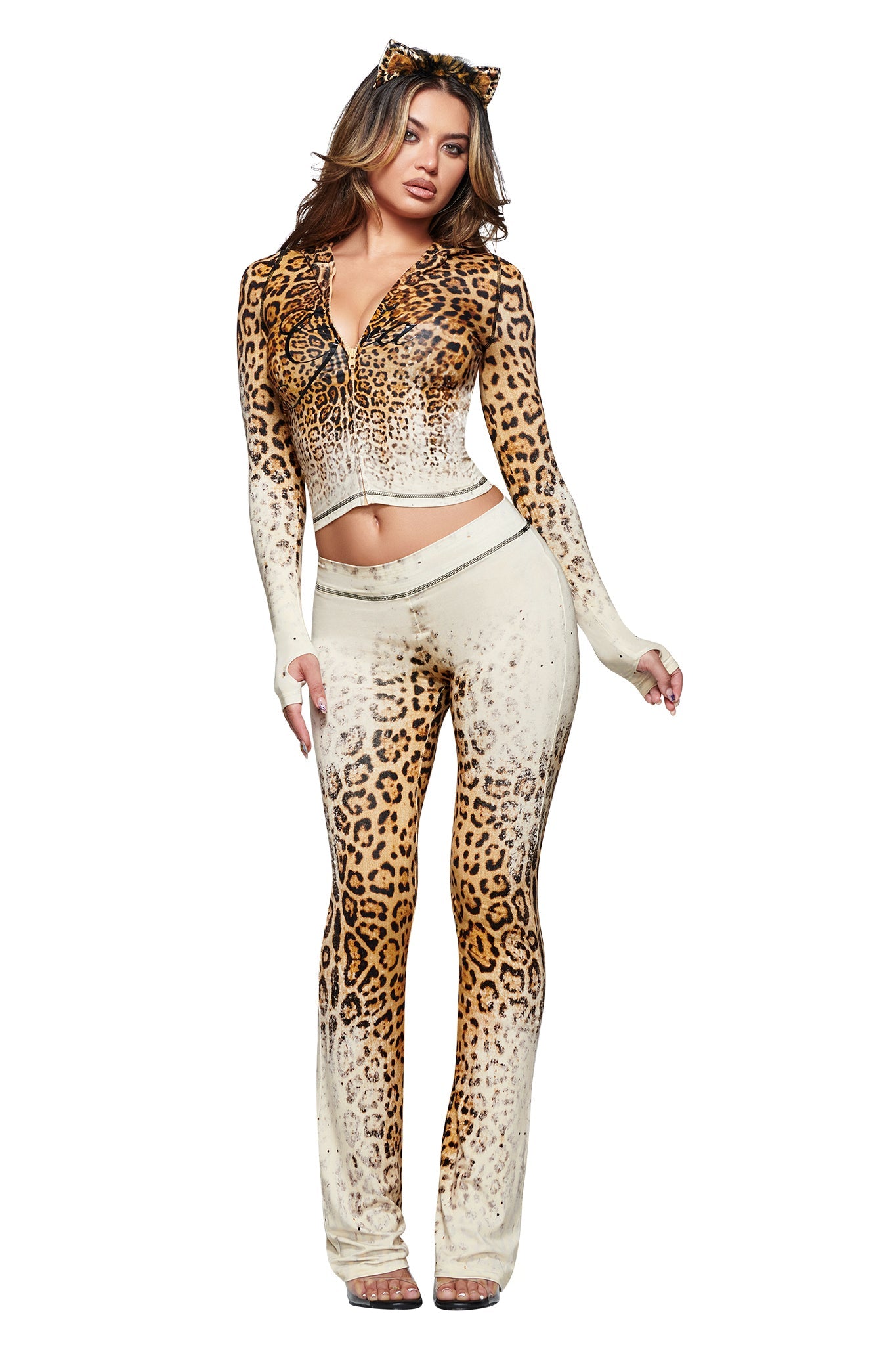 A woman poses confidently against a white background, wearing the I.AM.GIA BLARE HOODIE in Cream Faded Panthera—a bold, long-sleeve piece with a striking big cat print that channels fierce energy. Her outfit pairs flared pants and a matching cat ear headband for a coordinated, statement-making look.