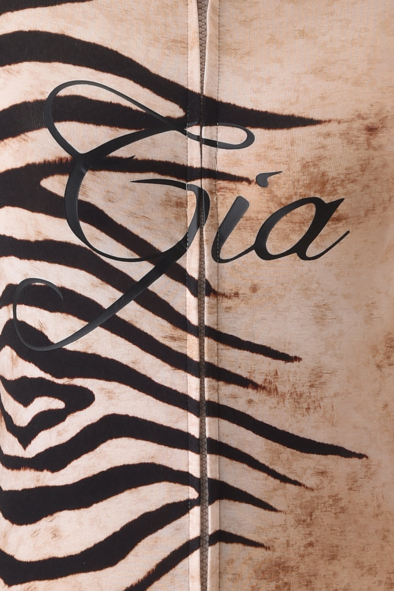 Close-up of the BLARE HOODIE - WILD SIDE by I.AM.GIA, featuring beige and black zebra-print bamboo fabric with "Gia" in bold black script across the center.