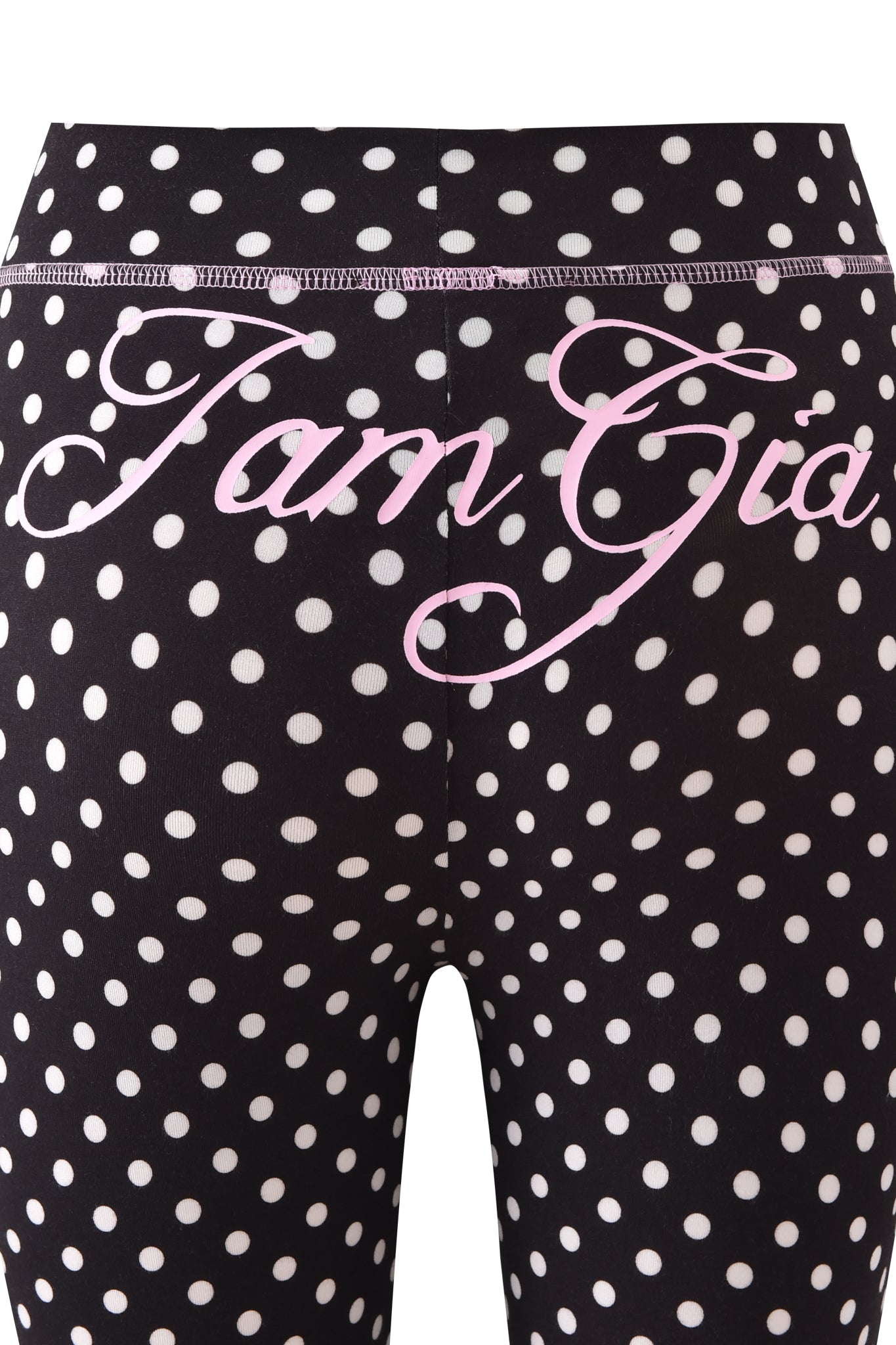 Close-up of the BLARE TRACKPANT – BLACK POLKA DOT by I.AM.GIA, featuring a bold polka dot print and pink cursive "I.AM.GIA" text on the back waistband.