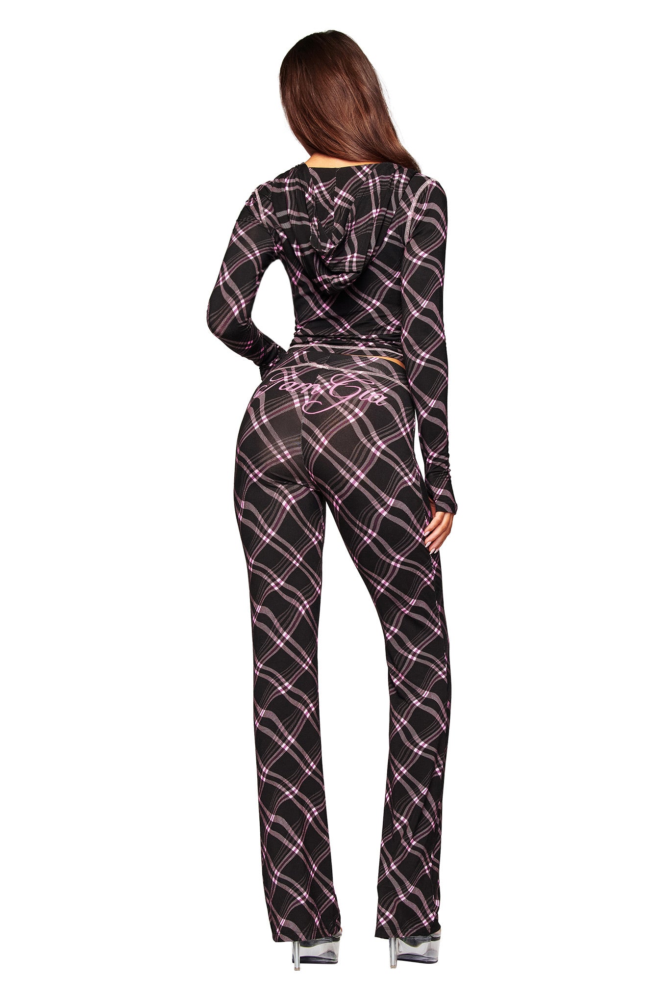 A woman with long brown hair wears high heels and the I.AM.GIA BLARE TRACKPANT in Black Warped Plaid, paired with a matching hooded top. The look is accented by the I.AM.GIA logo.