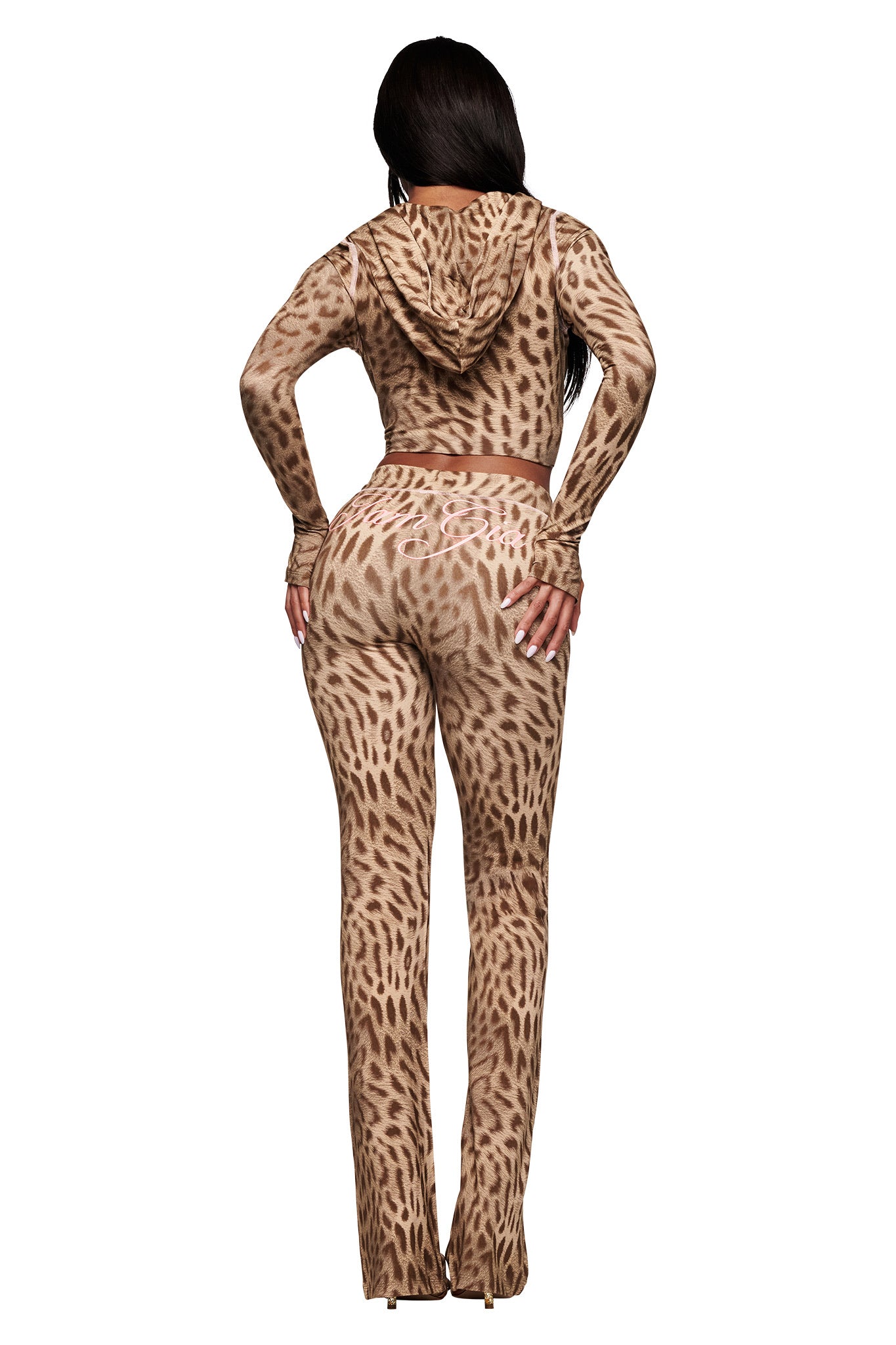 A woman faces away from the camera in the I.AM.GIA BLARE HOODIE - BLAZE CHEETAH, a fitted two-piece with long sleeves and flared pants. The brown and tan cheetah print stands out against the white background.
