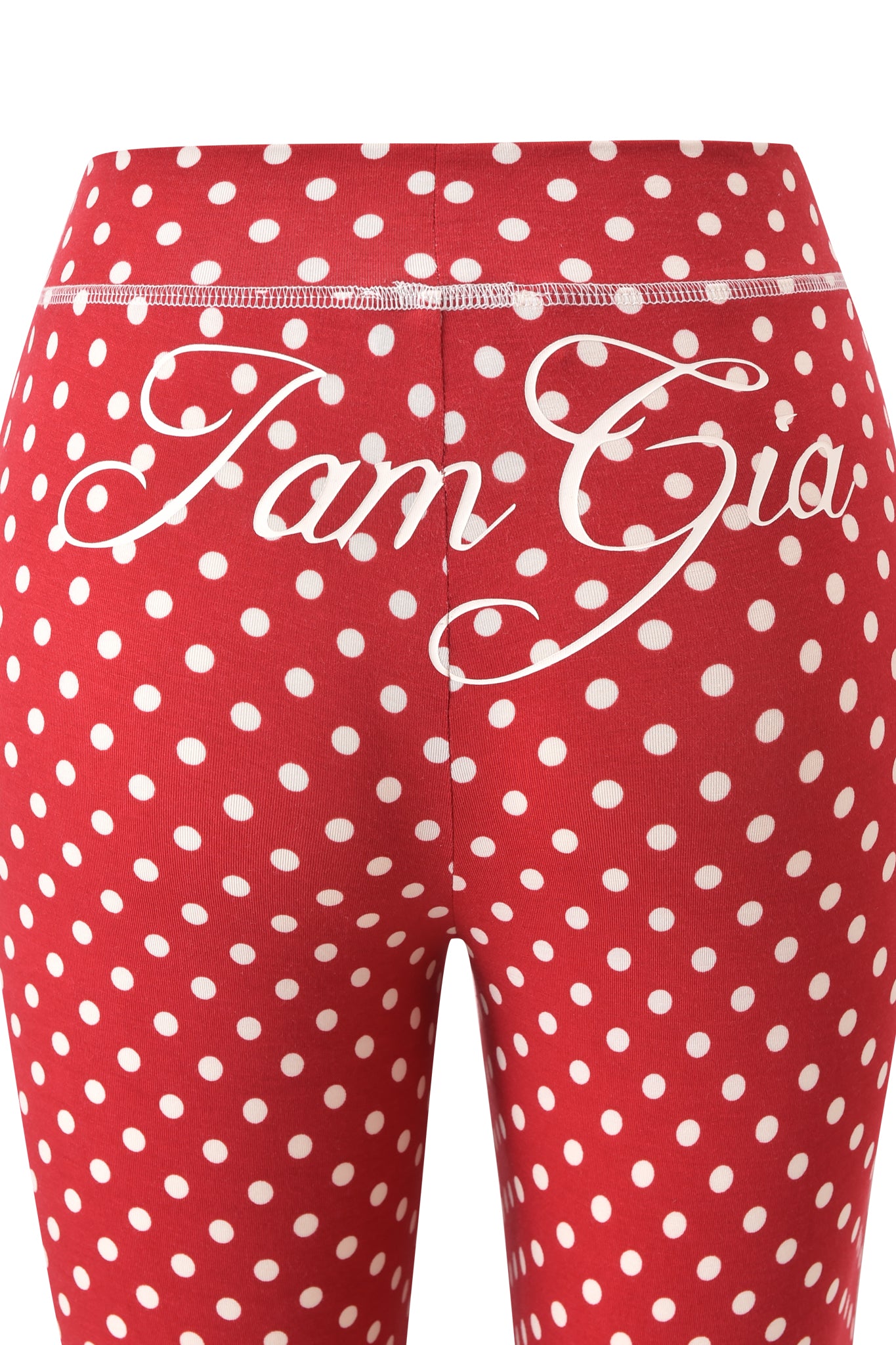 The image shows the back view of BLARE TRACKPANT - RED POLKA DOT by I.AM.GIA, featuring white polka dots and "I.AM.GIA" in cursive on the waistband.