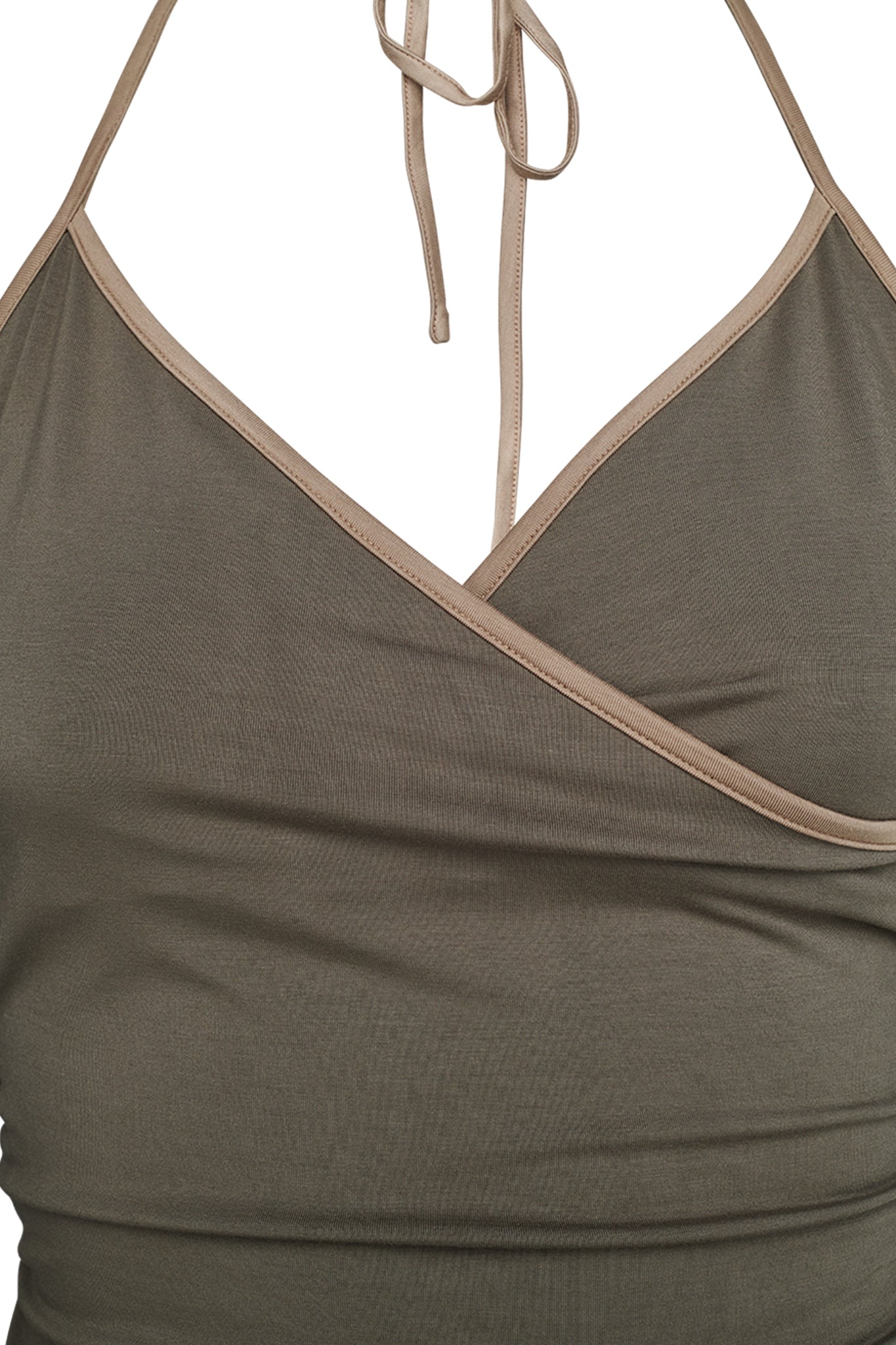 A close-up view of a woman's green Jannis Tank by I.AM.GIA, featuring a wrap-style design with thin straps tying behind the neck. The fabric appears soft and slightly fitted around the bust area.