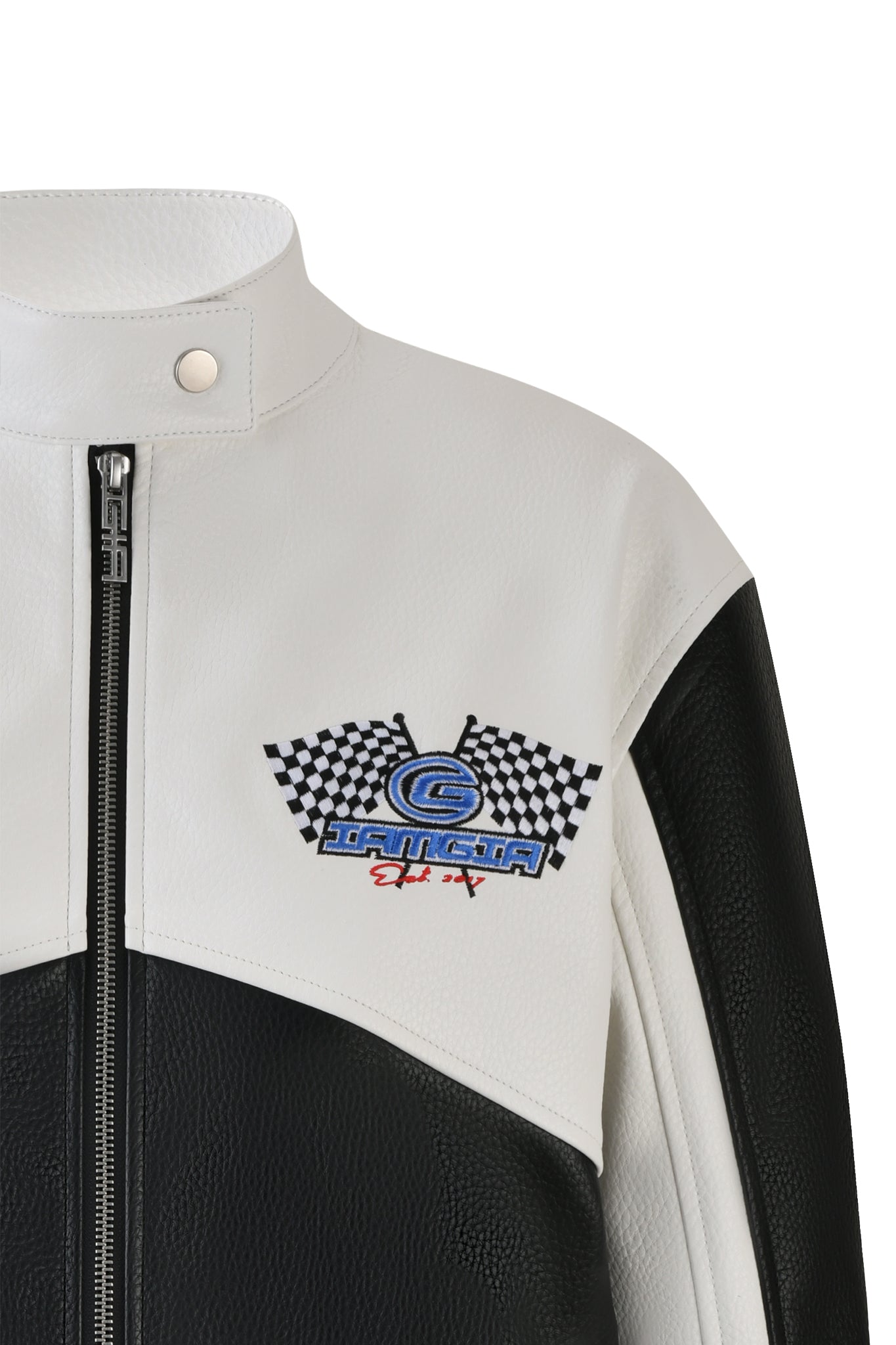 Close-up of the ROXY JACKET - WHITE by I.AM.GIA, showcasing its two-tone leather design with black and white panels. The jacket features a front zipper, a stand collar with a snap button, and an embroidered patch on the chest displaying two crossed checkered flags alongside stylized text.