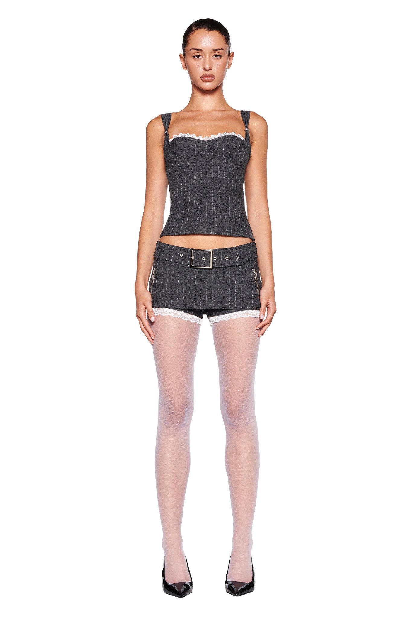 The MARRION CORSET - GREY : PINSTRIPE by I.AM.GIA is a dark grey pinstripe corset top that boasts subtle vertical stripes and a tailored silhouette. This sleeveless design features a structured bodice with a sweetheart neckline. The slightly textured fabric adds refinement, while the scalloped lace trim provides an elegant touch.