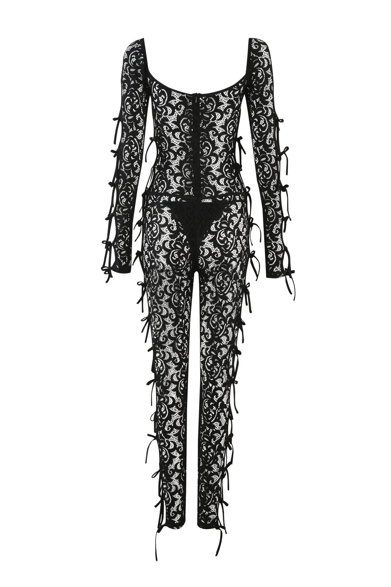 The LYSANDRA CATSUIT - BLACK from I.AM.GIA is a black lace jumpsuit with long sleeves, showcasing intricate floral patterns and cutouts. This form-fitting outfit is adorned with multiple bows along the sides of the arms, legs, and bodice.