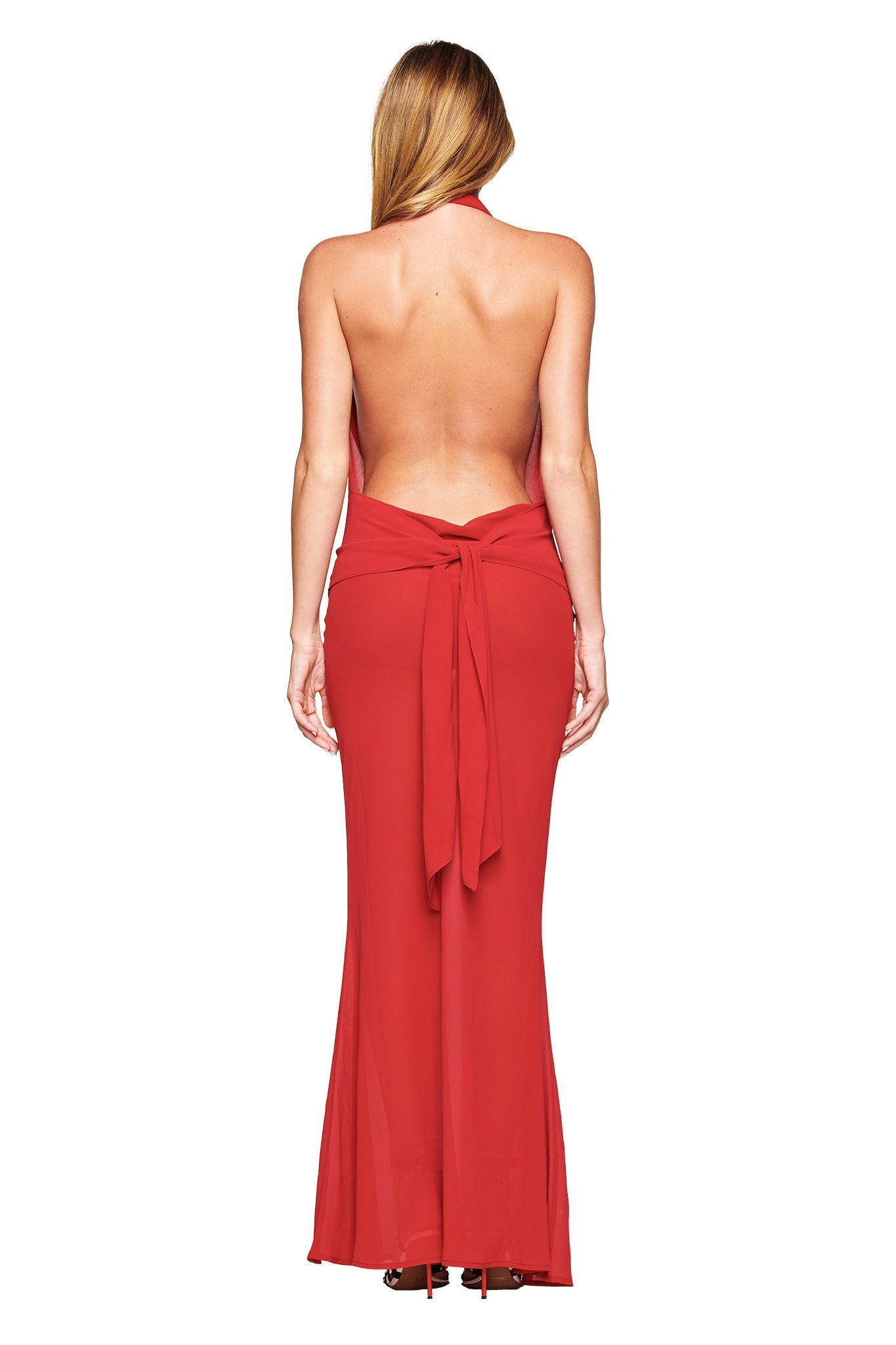 A woman with long, straight blonde hair is seen from behind wearing the I.AM.GIA KAHLO MAXI DRESS in red, a backless, floor-length style elegantly tied at the waist and highlighted against a plain white background.