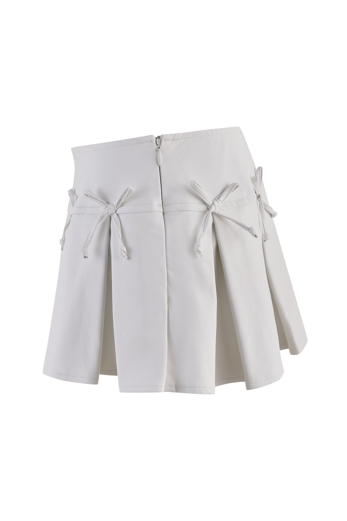 The EVERETTE SKORT - WHITE by I.AM.GIA is a white pleated mini skort featuring tied bow details on the front. It boasts an asymmetrical hemline, a low rise waist, and is crafted from smooth fabric. The bows add a decorative touch to its clean, modern design.