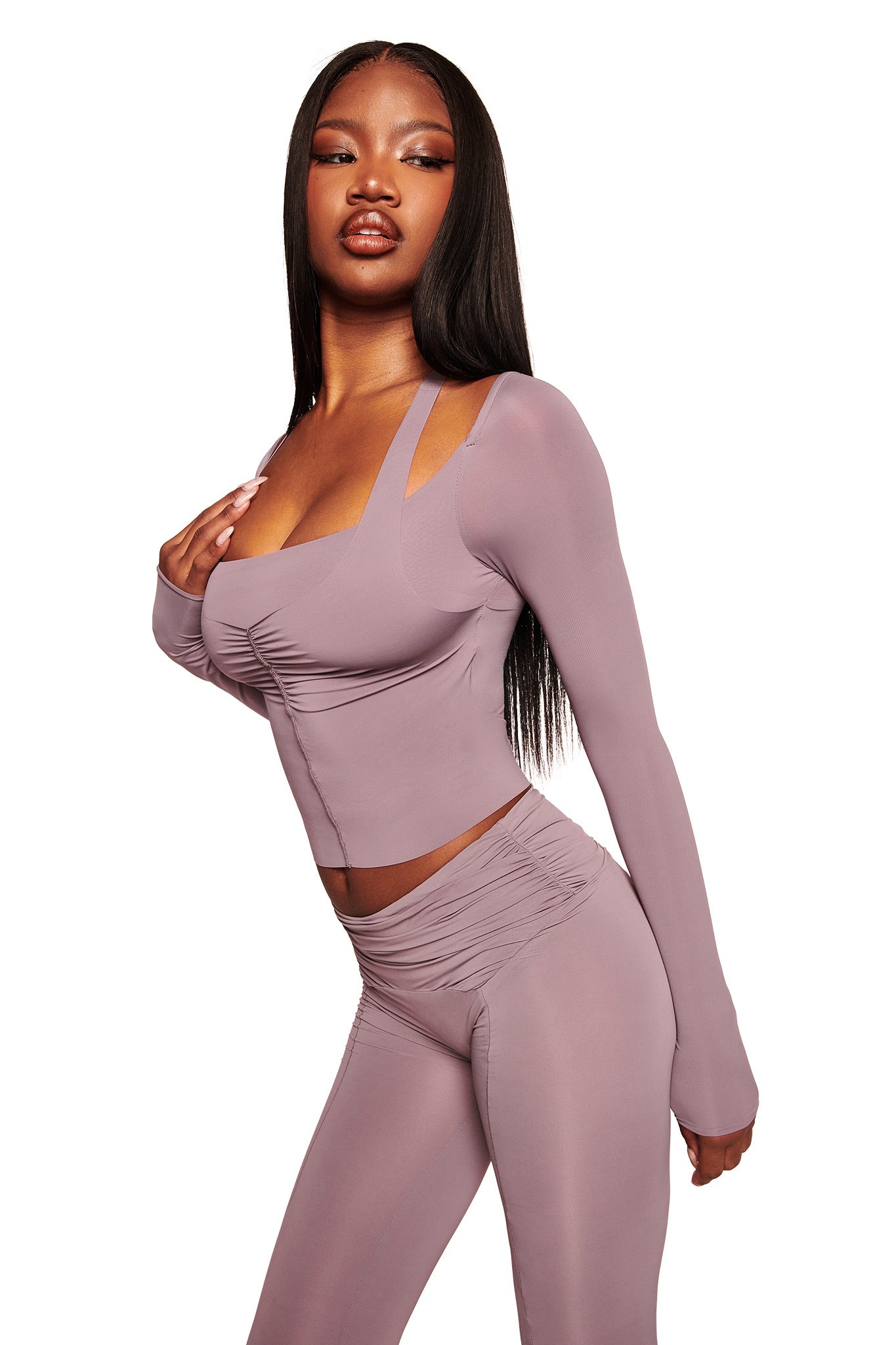 A woman poses confidently against a white background wearing I.AM.GIA’s NERINA LEGGING in Dusty Lilac, paired with a fitted, long-sleeve crop top for a stylish matching look.