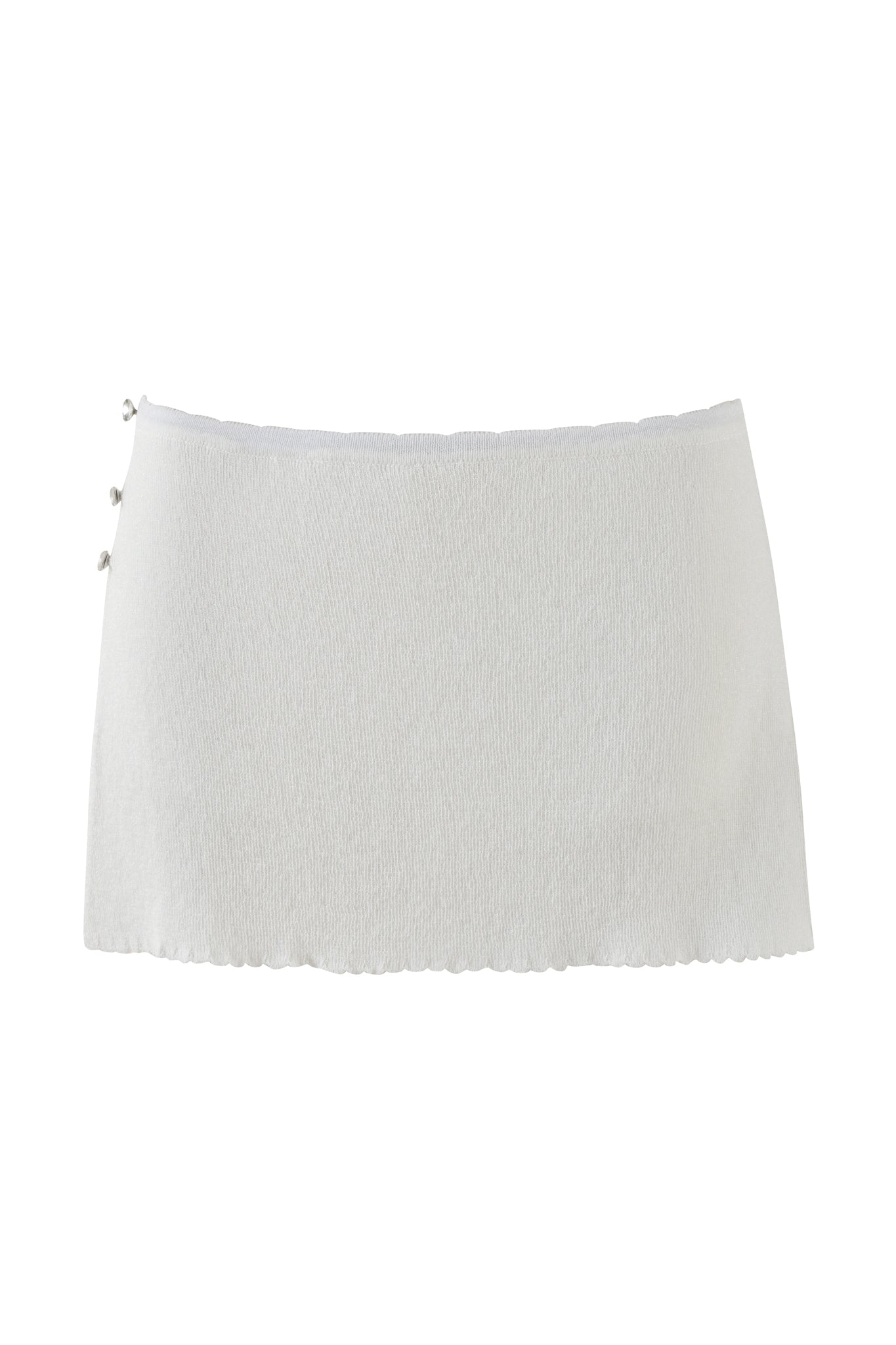 A SNOW WHITE skort from I.AM.GIA, created using shimmery lurex yarn, features a delicate scalloped edge and three decorative buttons on one side. The skort is showcased against a simple white backdrop, highlighting its elegant design.