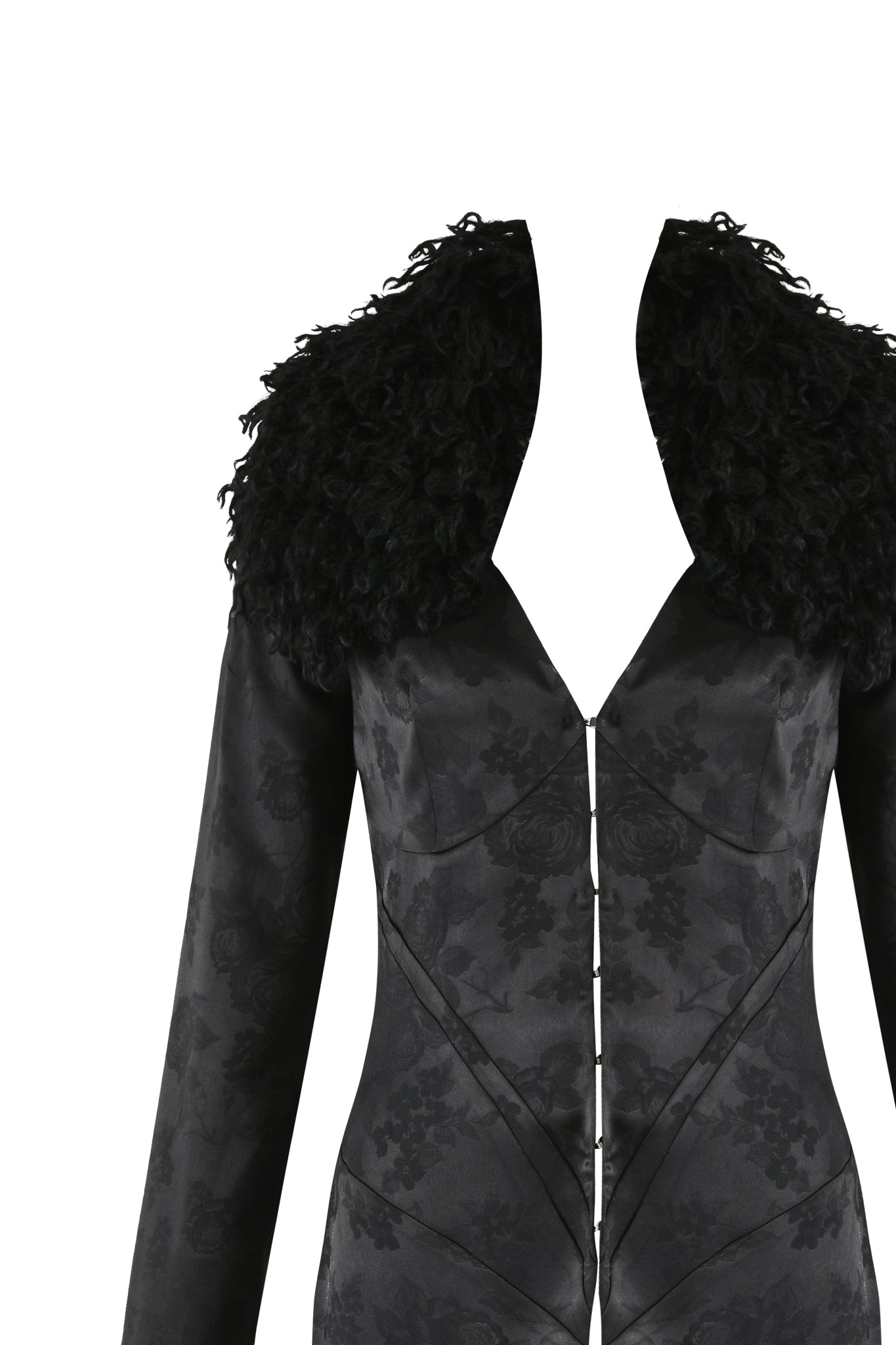The TAMERA COAT - BLACK by I.AM.GIA features a black floral jacquard design with a deep V-neck and a textured, fluffy faux Mongolian fur collar. The luxurious sheen of the fabric is complemented by front seam detailing that creates a sleek silhouette, all set against a plain white backdrop.