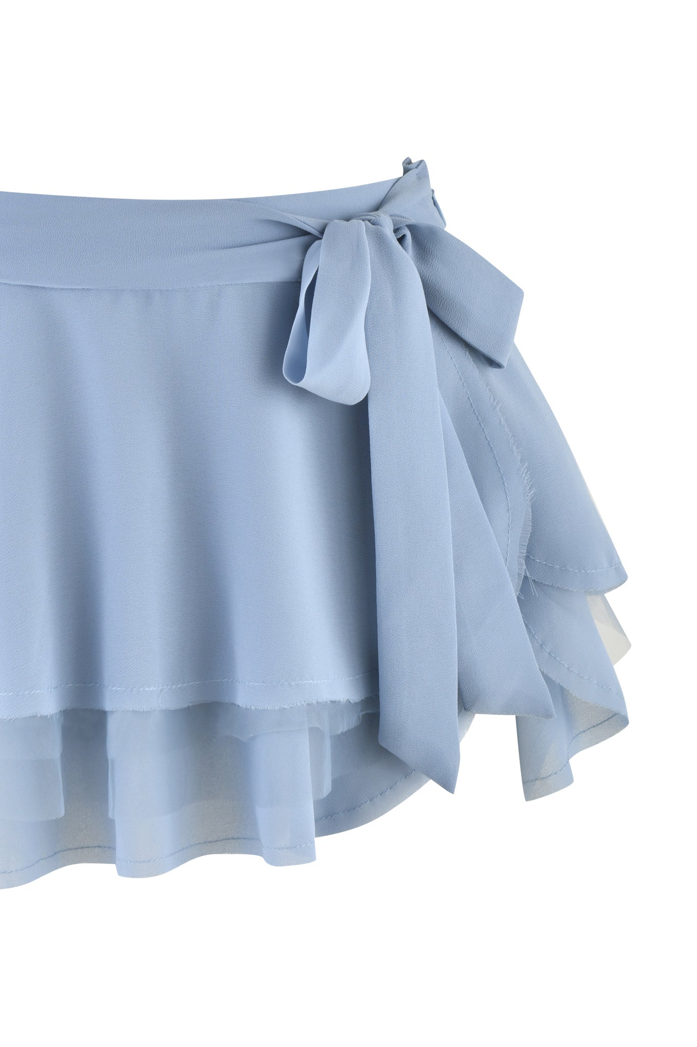 Introducing the QUEENIE MINI SKIRT in Steel Blue by I.AM.GIA: This enchanting chiffon skirt features light blue georgette fabric with layered ruffles and a chic tied bow at the waist. Its soft, flowing appearance exudes a delicate and elegant charm.