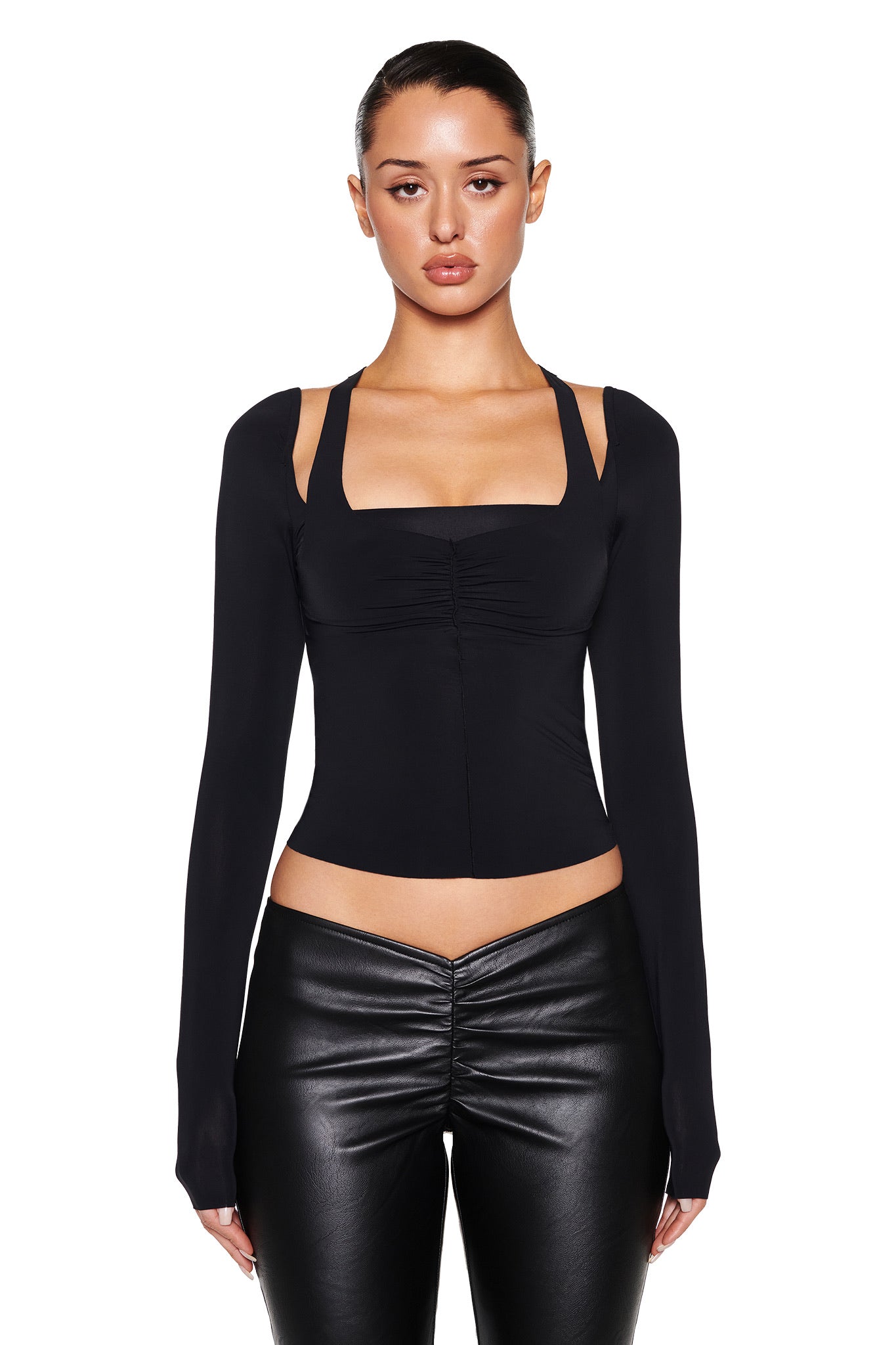 A person faces the camera against a white background, wearing I.AM.GIA's black long-sleeve square-neck top and NEAVAH PU PANT - BLACK with a V-shaped waistband. Their hair is pulled back, and they maintain a neutral expression.
