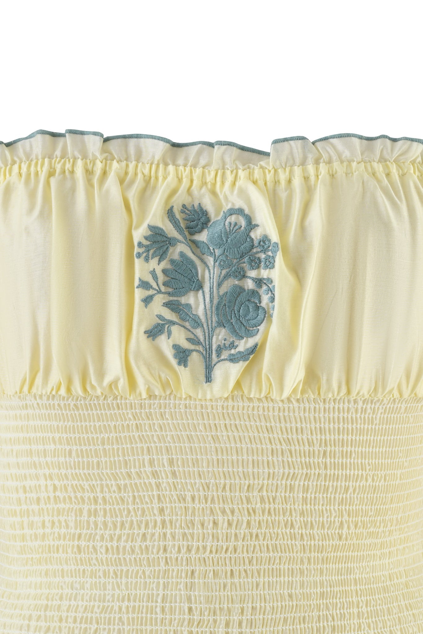The CLOVER TOP - YELLOW by I.AM.GIA is a lightweight cotton fabric with smocking details, featuring a blue floral embroidered design of roses and leaves at the center for a decorative touch.