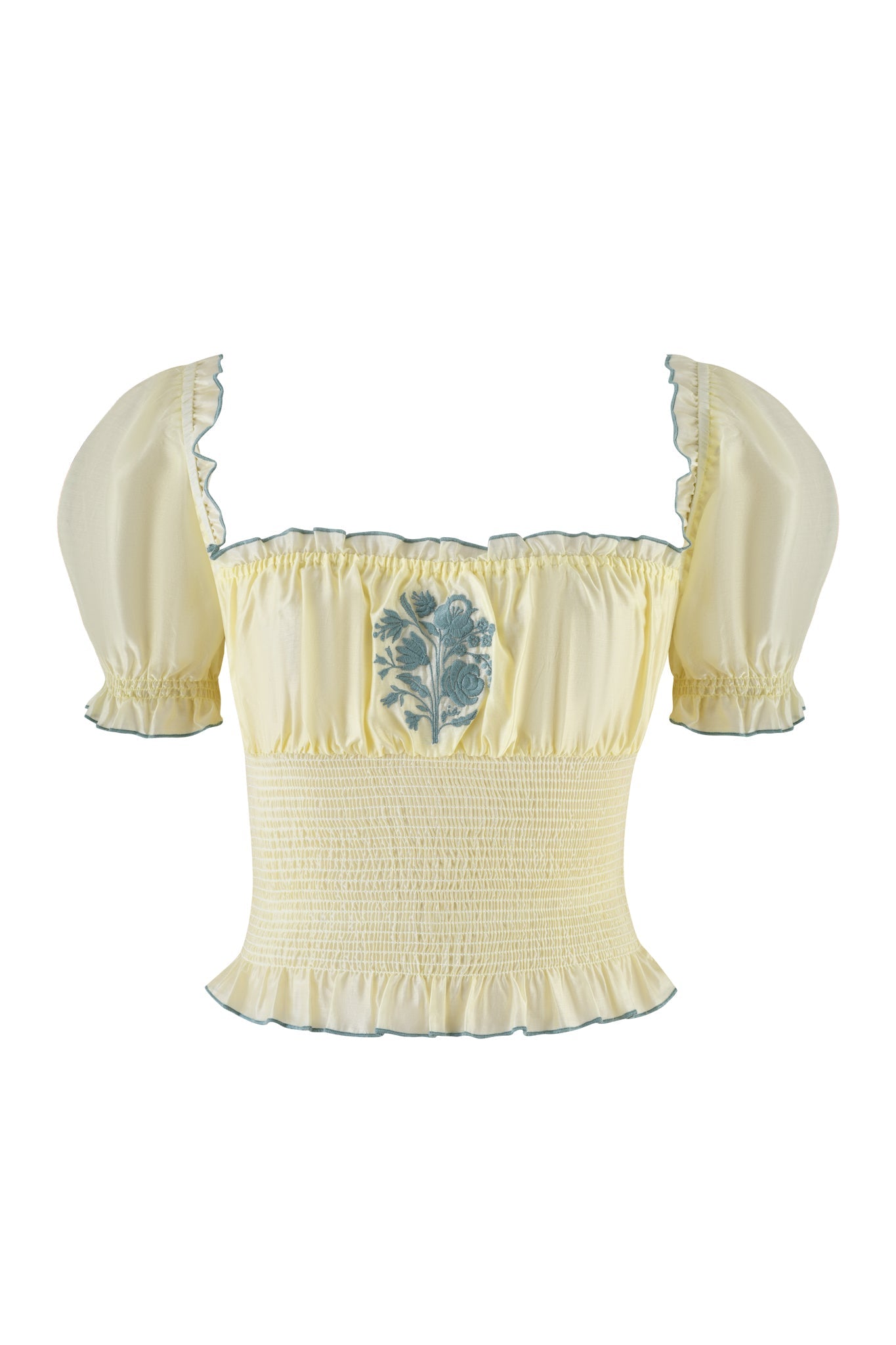 The CLOVER TOP - YELLOW by I.AM.GIA is an off-the-shoulder smocked top featuring puffed sleeves, an elastic ruffled hem, and a subtle green floral design at the center. Crafted from lightweight cotton, it has delicate green trim on the cuffs and neckline for added elegance.