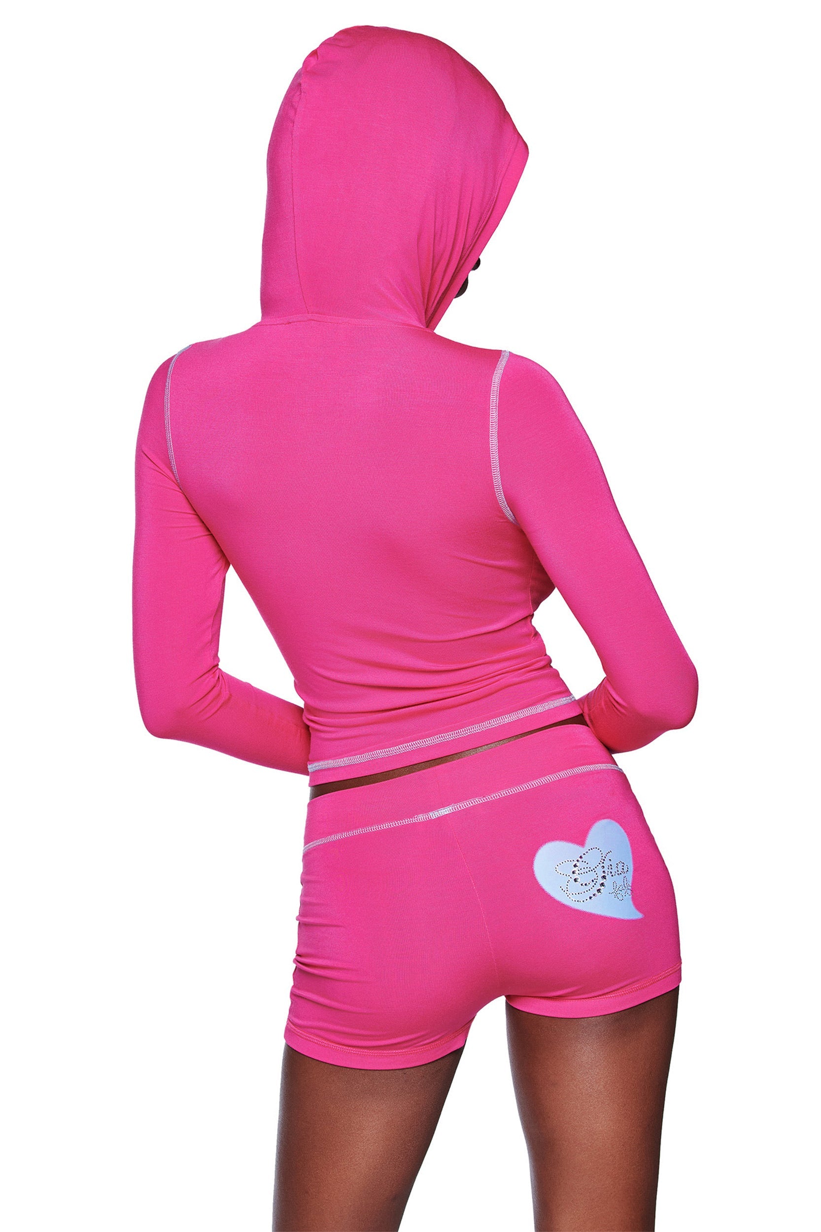 A person faces away from the camera in a bright pink hooded long-sleeve top and matching I.AM.GIA FAFI BLARE SHORT - HOT PINK, which features a heart graphic and decorative text on the right side.