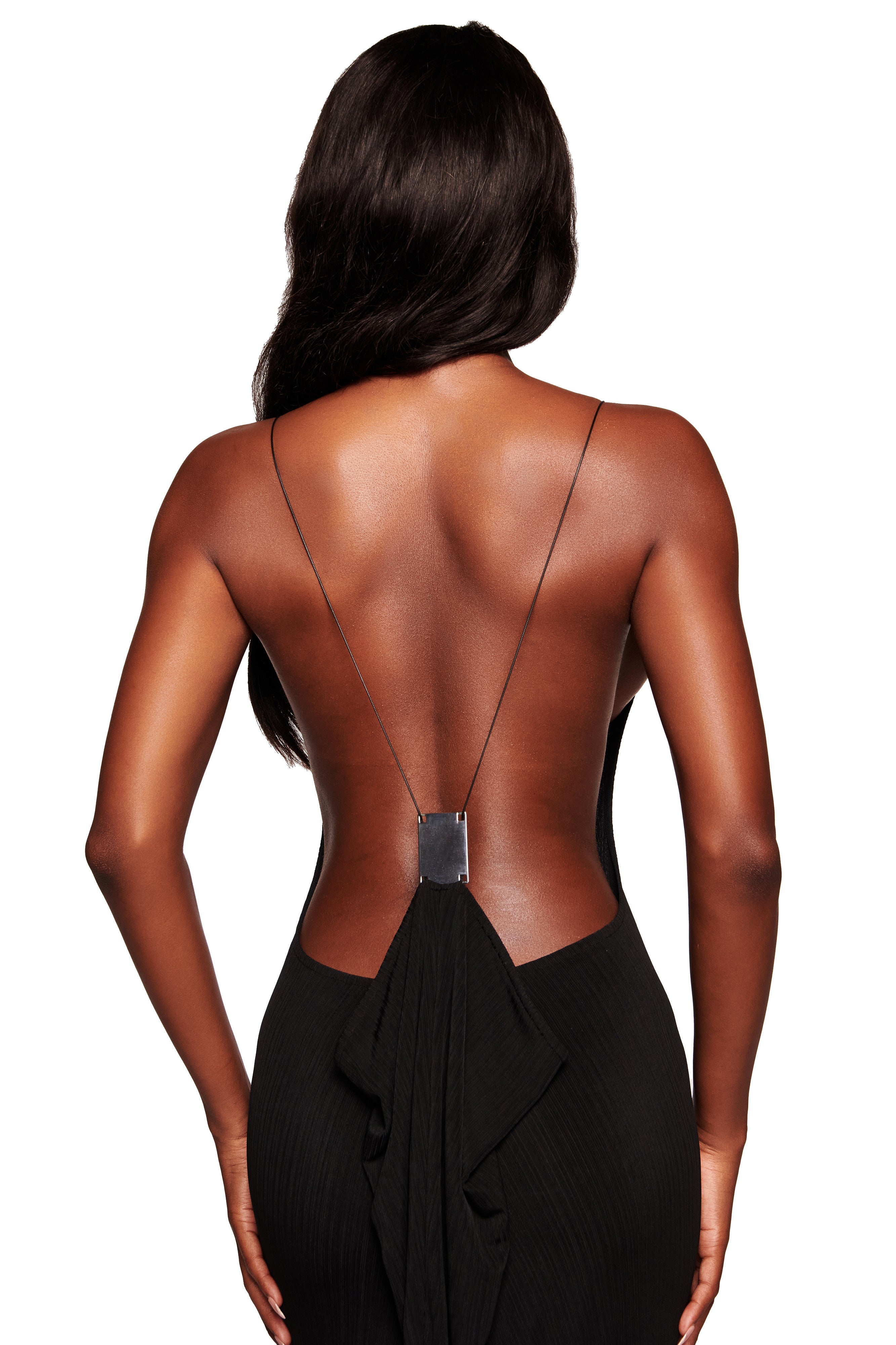 A woman with long dark hair is seen from the back wearing the I.AM.GIA SIMONE MAXI DRESS in black, featuring thin straps and a ruffled lower back, set against a white background.