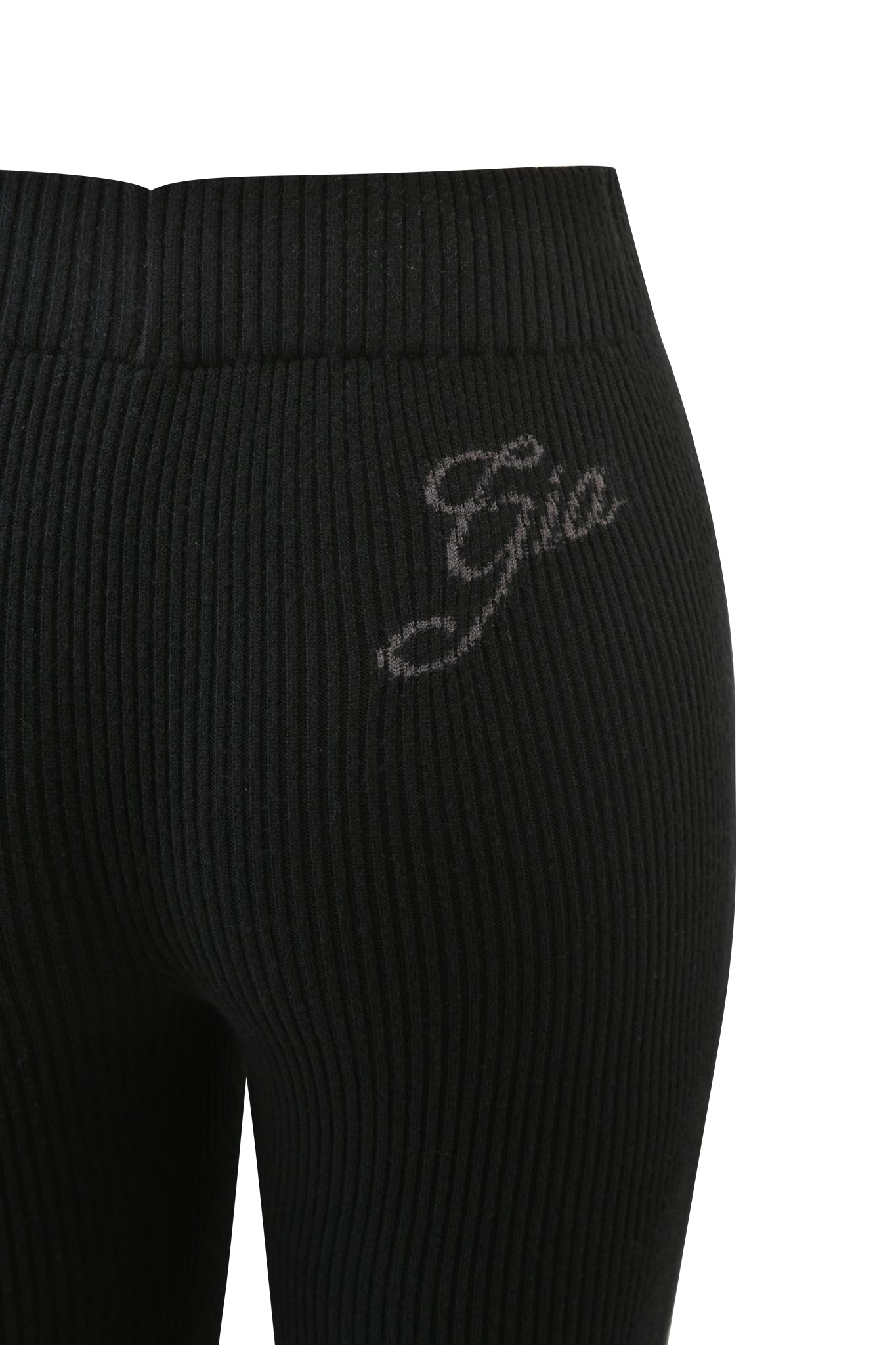 Close-up of the upper back of the I.AM.GIA BLARE KNIT TRACKPANT in black, featuring a mid-rise elasticated waistband and "Gia" embroidered in a light color on the right hip.