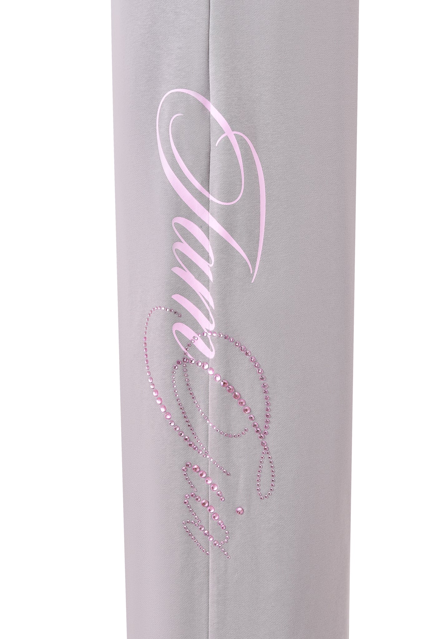 A close-up of the KADE PANT - GREY by I.AM.GIA, showcasing a wide leg with "Juicy" in pink script, adorned with pink rhinestones and a printed outline.