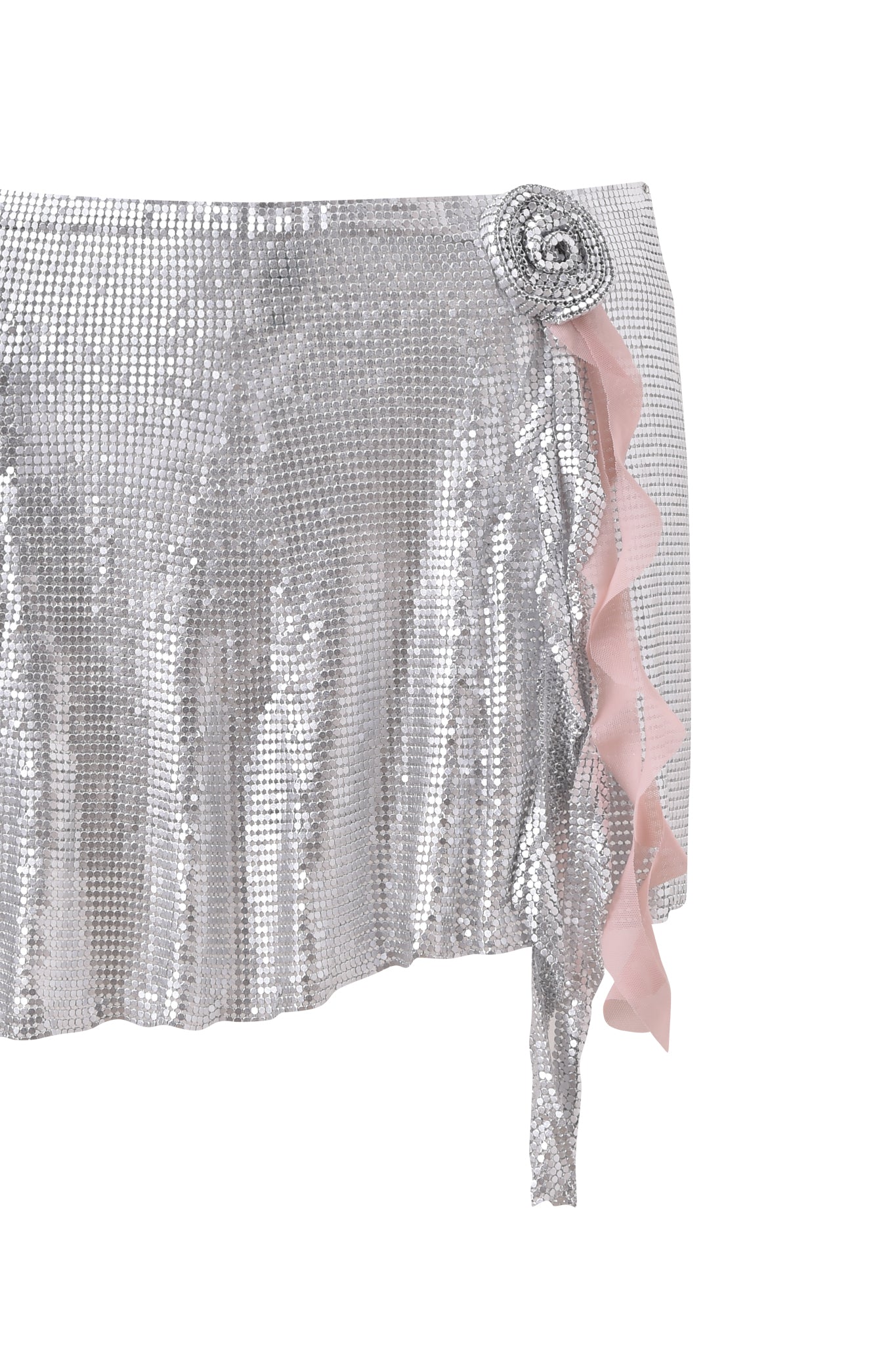 The MILANA MINI SKIRT - SILVER by I.AM.GIA is a shiny silver chainmail mini skirt with a grid-like texture, adorned with a silver rose and pink ruffle detail on the right side.