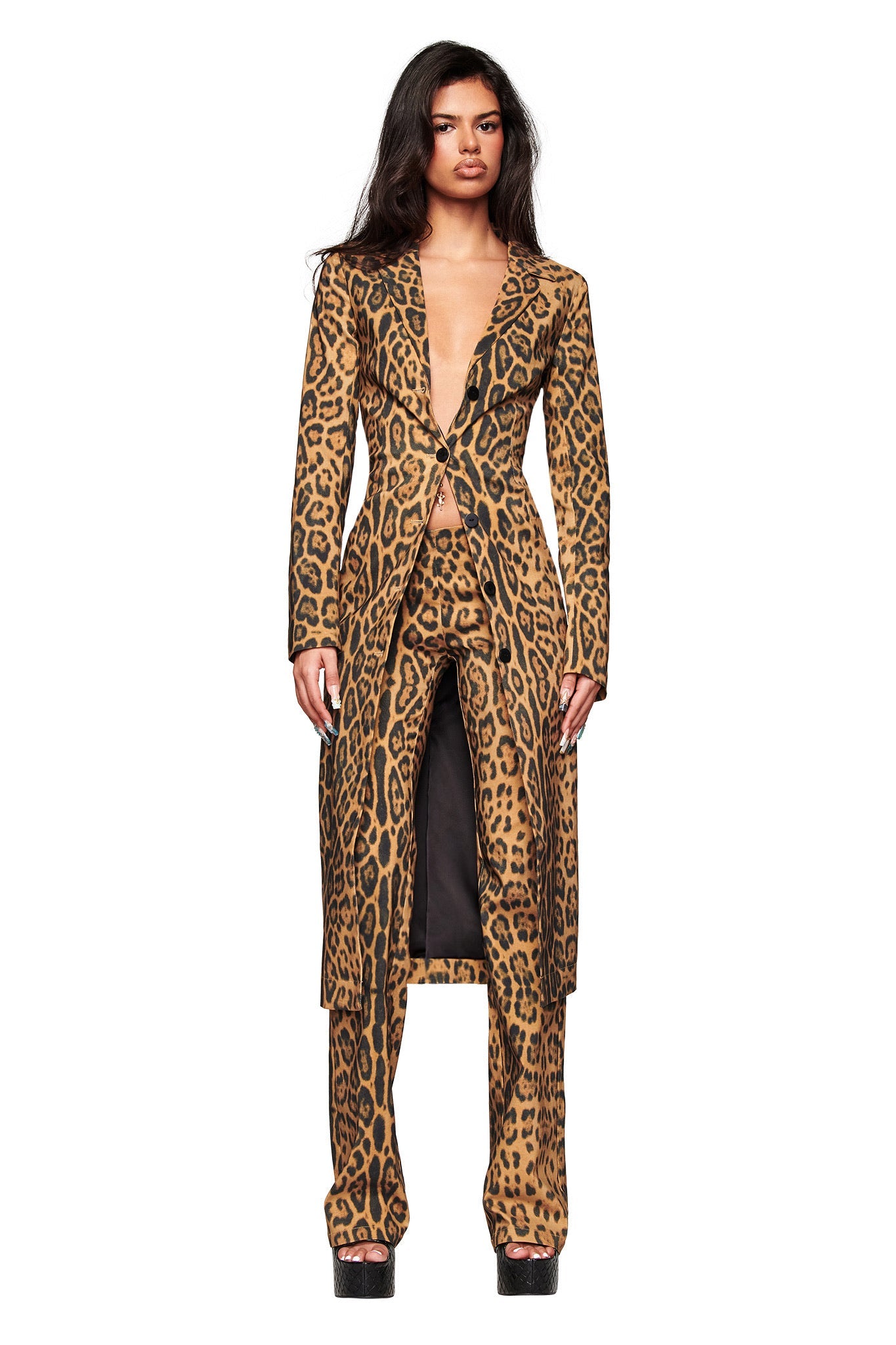 A person wears the I.AM.GIA UMA PANT - PANTHERA with a coordinating leopard-print coat and black platform shoes, posing against a plain white background.