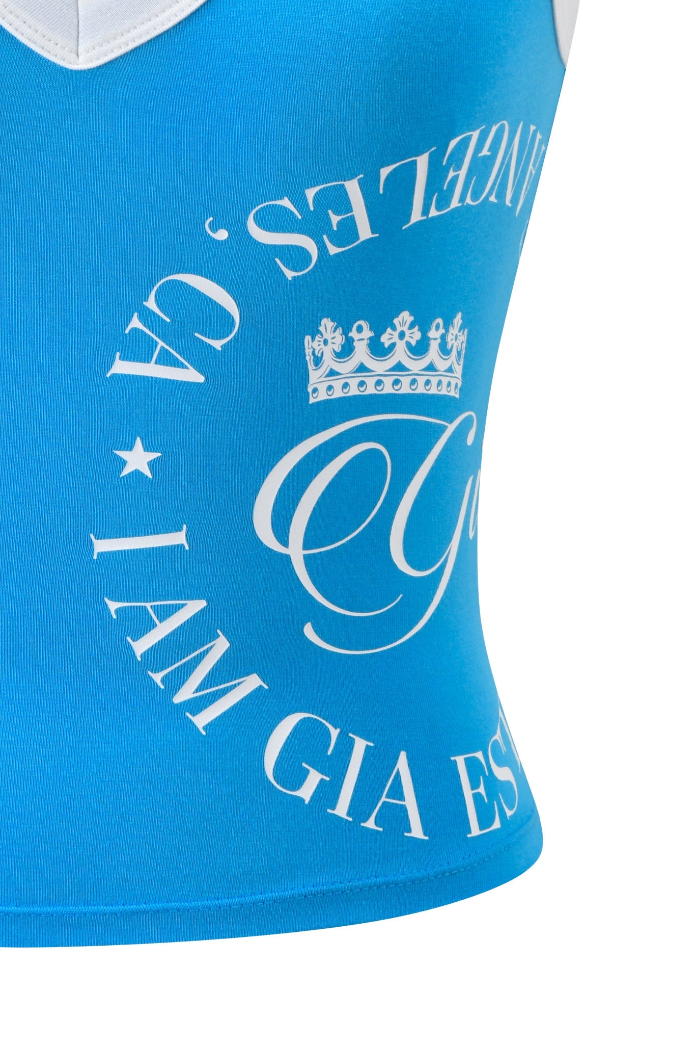 Close-up of the BLARE BIND TANK in sky blue by I.AM.GIA, featuring white circular text, a crown graphic, and partial "GIA" and "ANGELS" lettering. The white neckline edge is visible at the top.