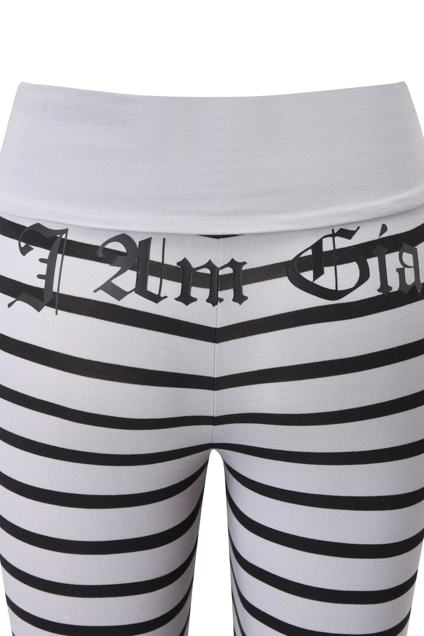 A close-up of a person wearing I.AM.GIA’s BLARE FOLDOVER TRACKPANT—grey and black striped pants with bold Gothic-style text on the waistband and hips.