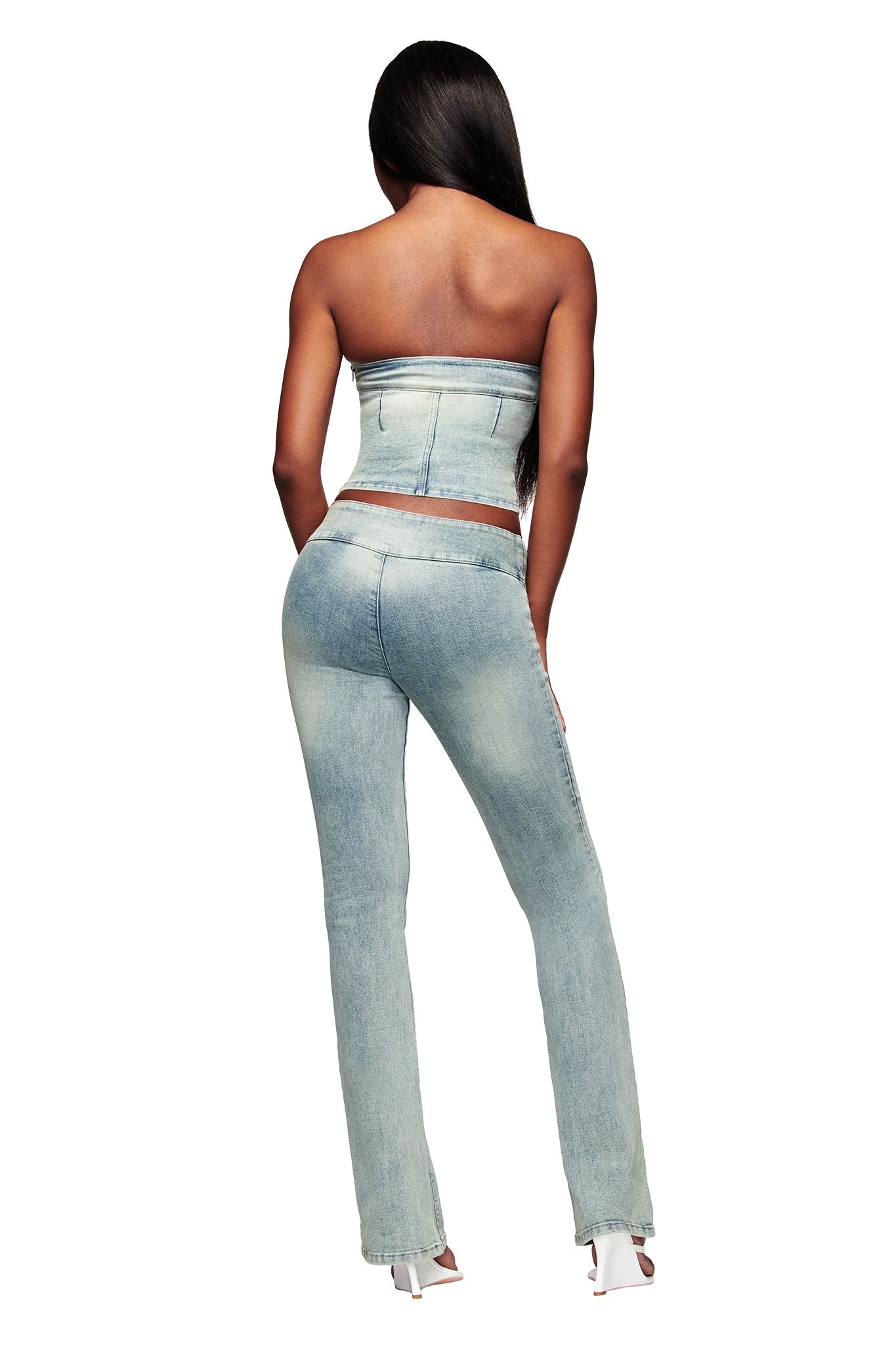 A woman with long straight hair models the I.AM.GIA JENN DENIM BOOB TUBE in blue, paired with high-waisted jeans and white heels, standing with her back to the camera against a white background.