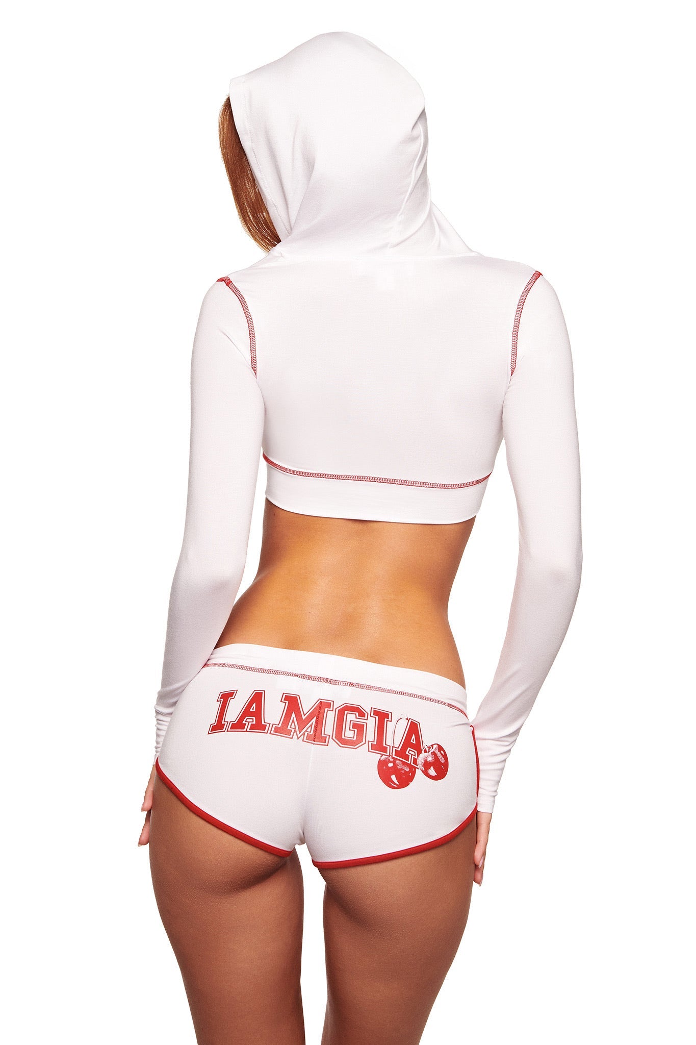 A woman is seen from behind in a white cropped hoodie and I.AM.GIA BLARE DOLPHIN SHORT in white, featuring a mini length with red trim and "IAMGIA" plus boxing gloves printed in red on the back.