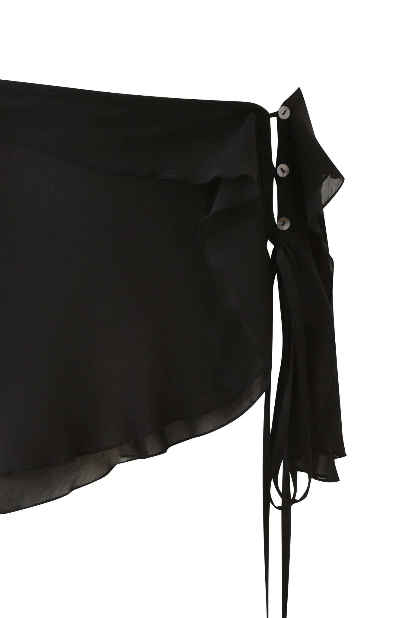 Close-up of the I.AM.GIA PORTIA RUFFLE MINI SKIRT - BLACK, a black georgette wrap mini skirt with semi-sheer, flowy fabric, ruffled asymmetrical hem, and a side tie with grommet detail against a white background.