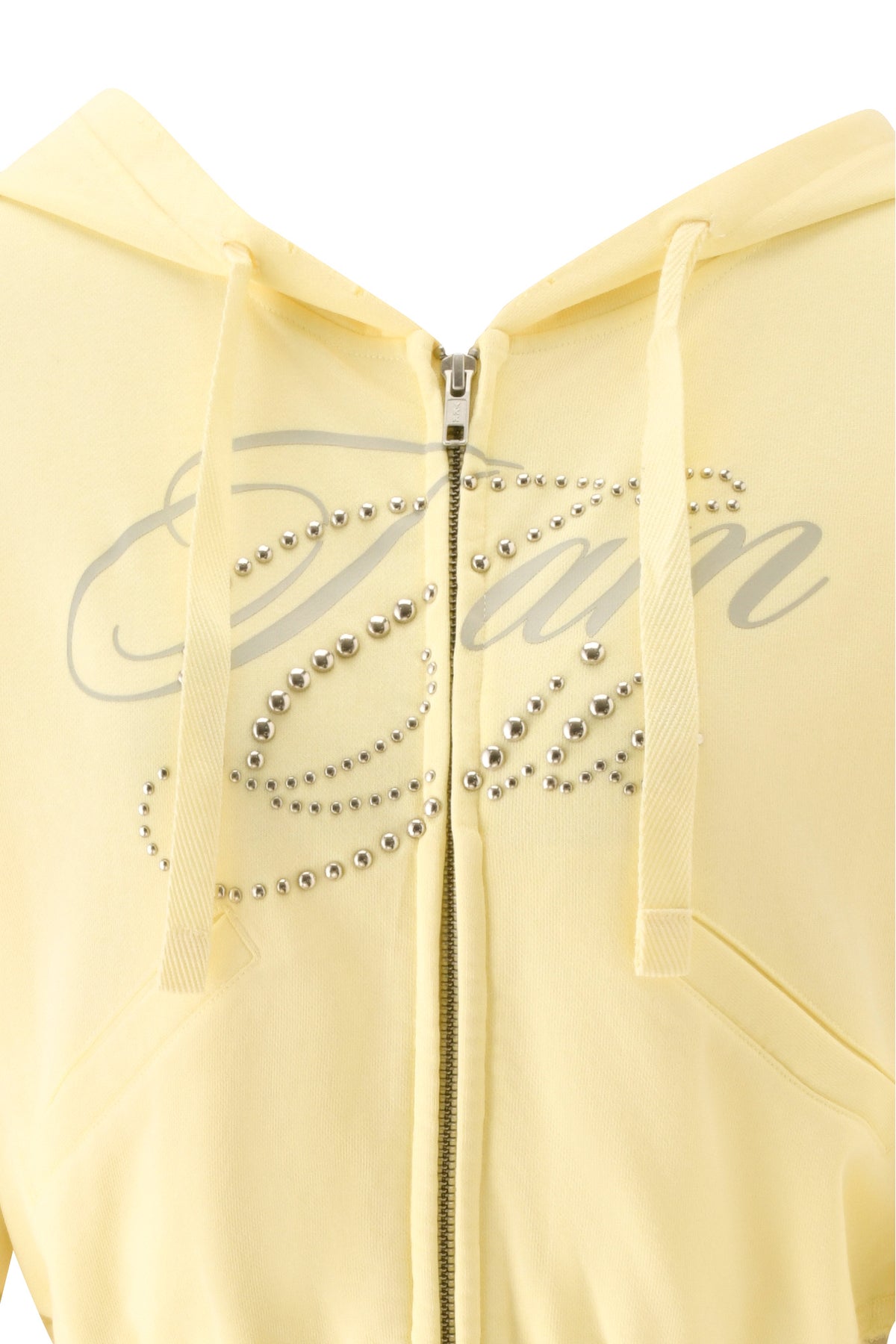 A close-up of the VEDA JACKET - YELLOW by I.AM.GIA, a yellow zip-up hoodie adorned with an oversized GIA script rhinestone design and the word “Dior” in elegant cursive across the front.
