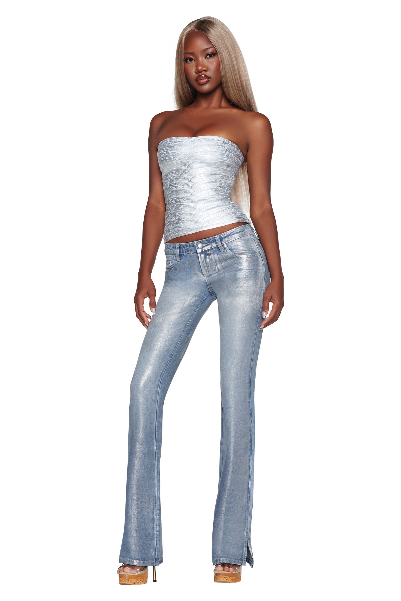 A woman wearing the I.AM.GIA RENATA JEAN in Silver Metallic Wash stands against a white background, styled with a silver strapless top and beige platform heels.