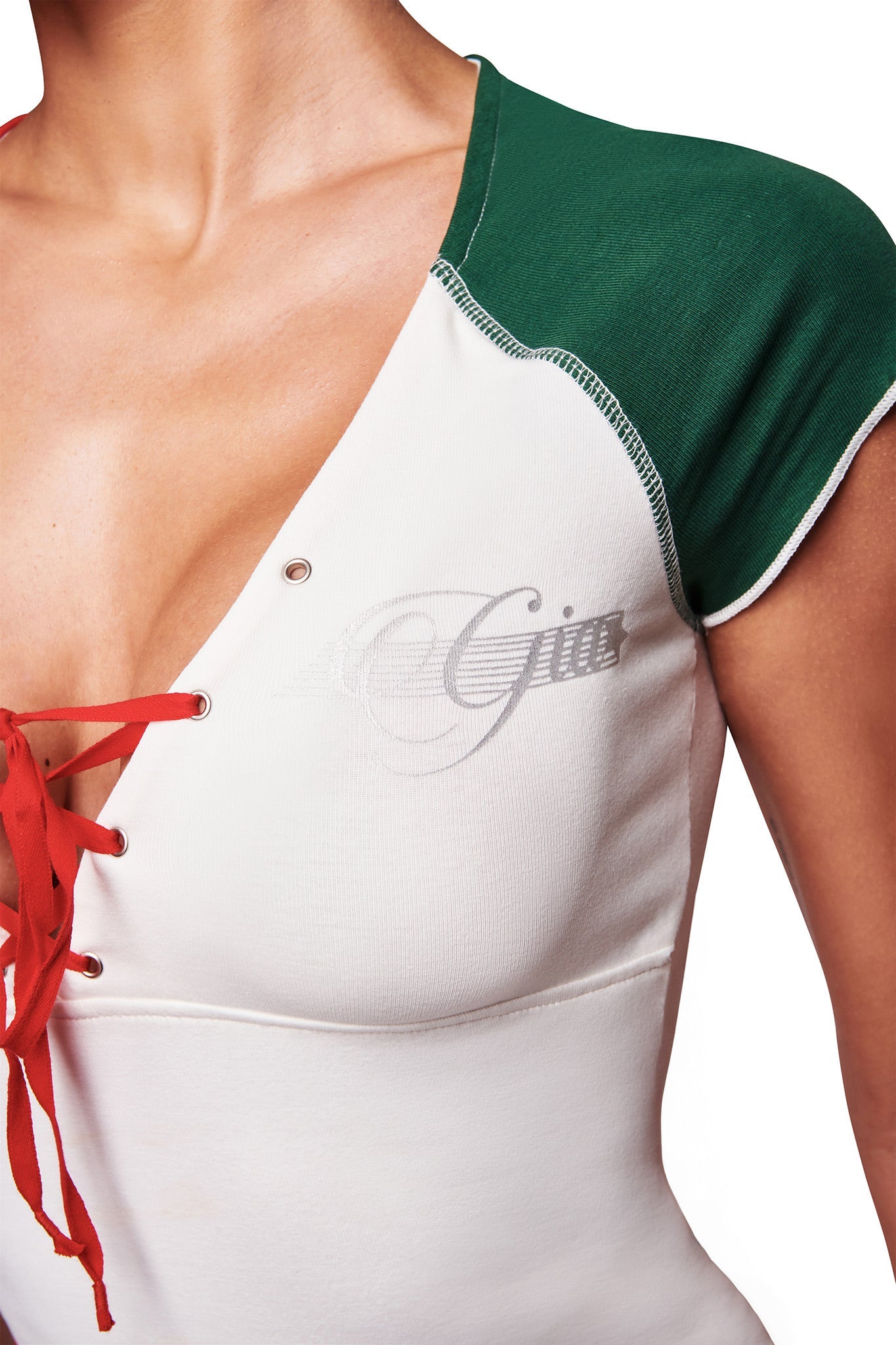A close-up shows a person wearing the I.AM.GIA NOVIA LACE-UP T-SHIRT AND HEADBAND in white, featuring red lace-up detailing and stitched lettering, focusing on the upper torso and neckline against a white background.
