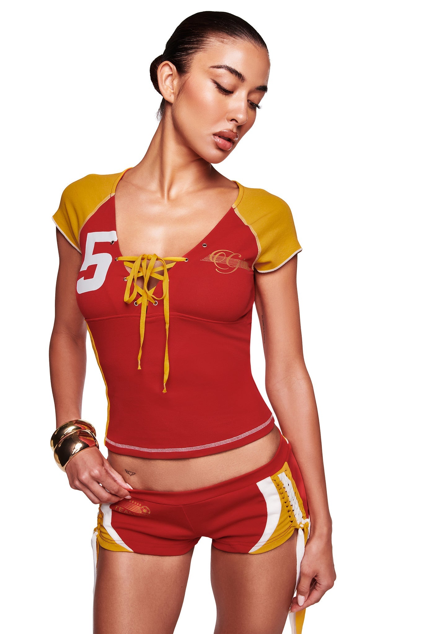A woman in the I.AM.GIA NOVIA LACE-UP T-SHIRT AND HEADBAND in red poses against a white background, looking down and to the side.