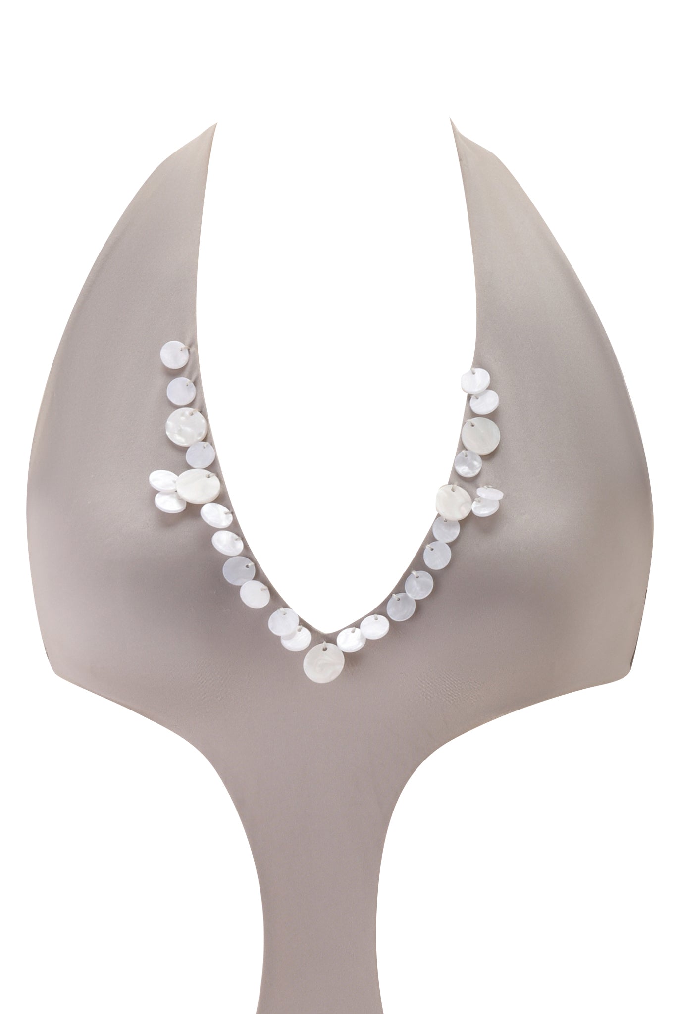 A sculptural, abstract mannequin showcases the I.AM.GIA GENE EMBELLISHED ONE PIECE SWIMSUIT - PEARLESCENT, featuring large iridescent white discs along a deep V neckline. The background is plain white.
