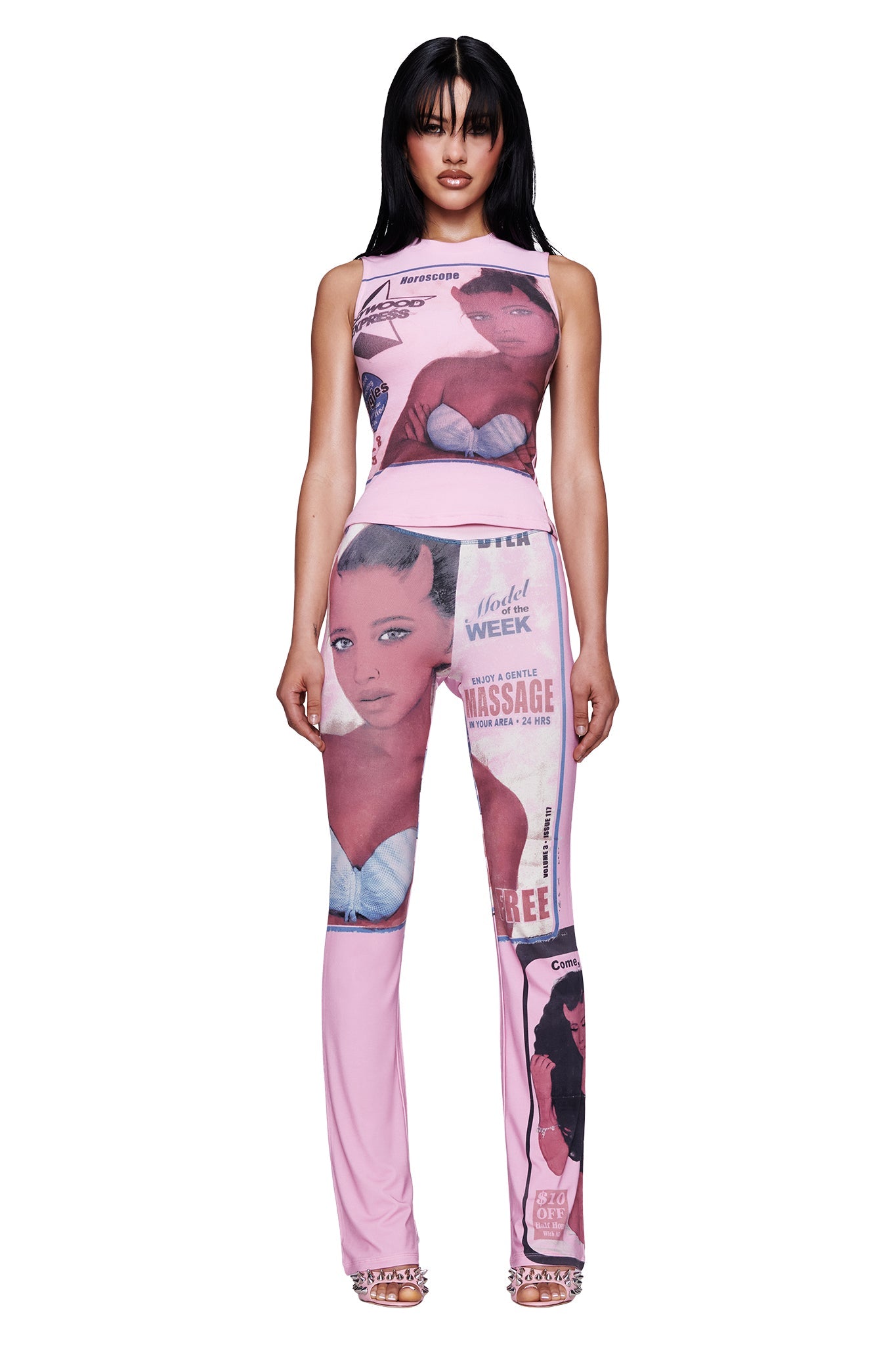 A woman stands facing forward against a plain white background, wearing a sleeveless pink top and the I.AM.GIA T-REX BLARE TRACKPANT in Pink, which features vintage-inspired magazine covers and female portraits.