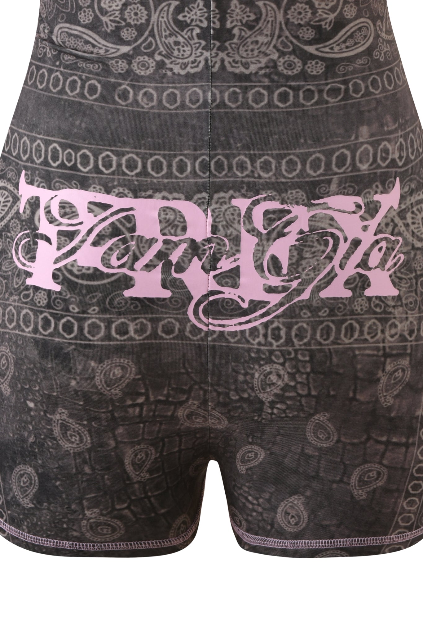 Close-up of a person wearing the I.AM.GIA T-REX BLARE SHORT SLEEVE ROMPER in Charcoal Bandana, featuring gray-black patterned fabric with pink stylized text across the back. The print combines paisley and geometric designs for a bold festival statement, showcasing an exclusive look from I.AM.GIA.