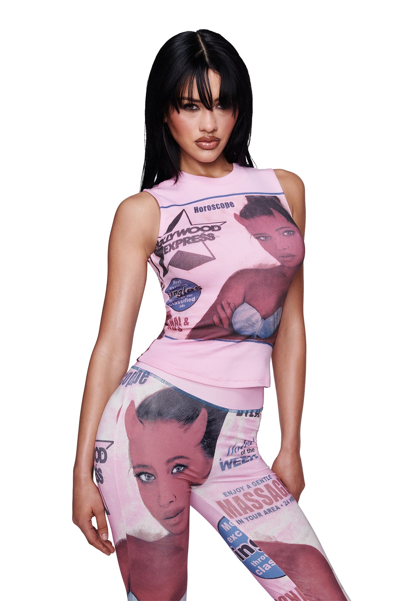 A woman with straight black hair wears the I.AM.GIA T-REX COURTNEY TANK in pink along with matching pants adorned with magazine-style prints of illustrated female faces and text, posing against a white background.