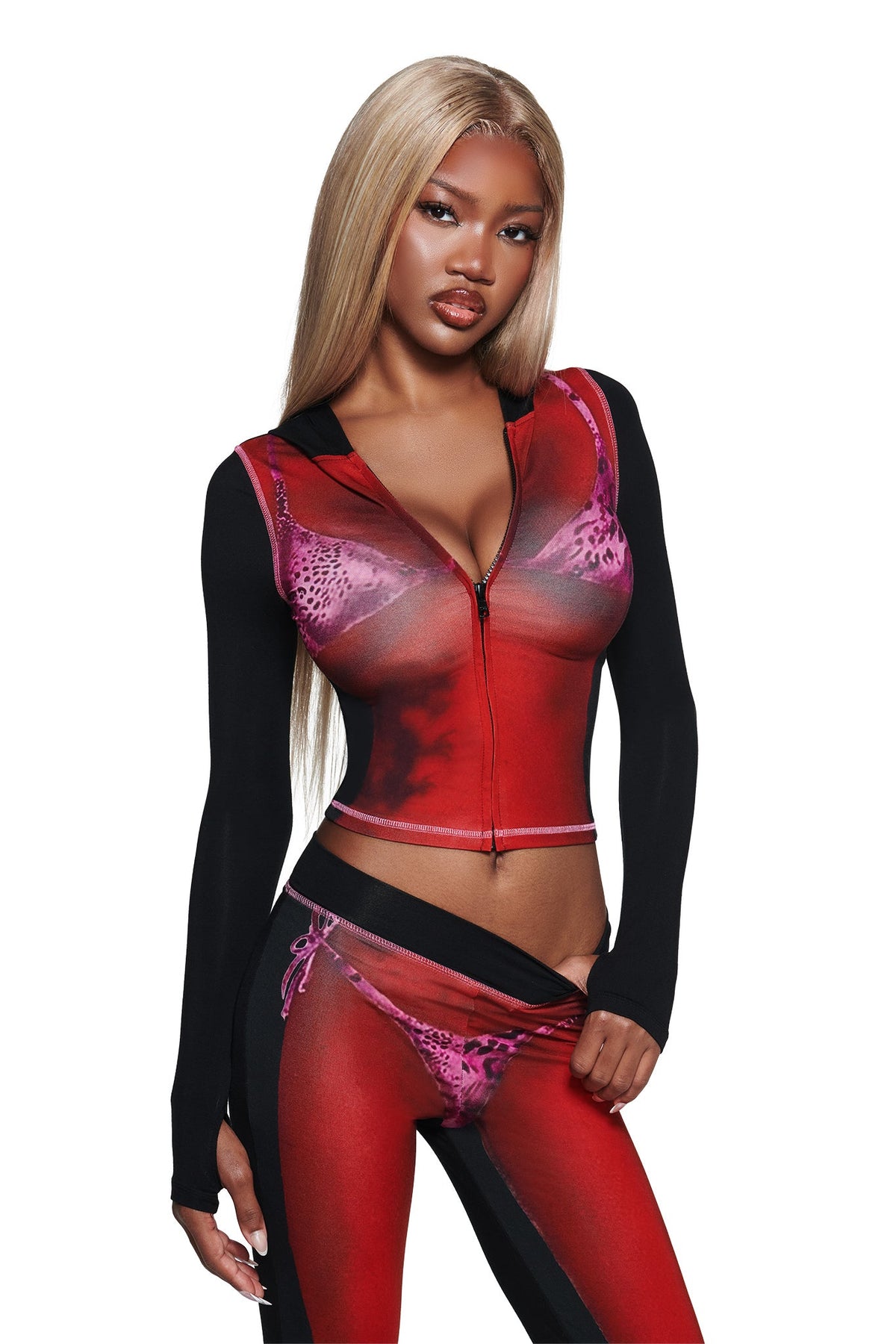 A woman with long blonde hair poses against a white background, wearing the I.AM.GIA T-REX SPRAY BODY BLARE HOODIE - BLACK, featuring a fitted animal print design, front zipper, and black sleeves.