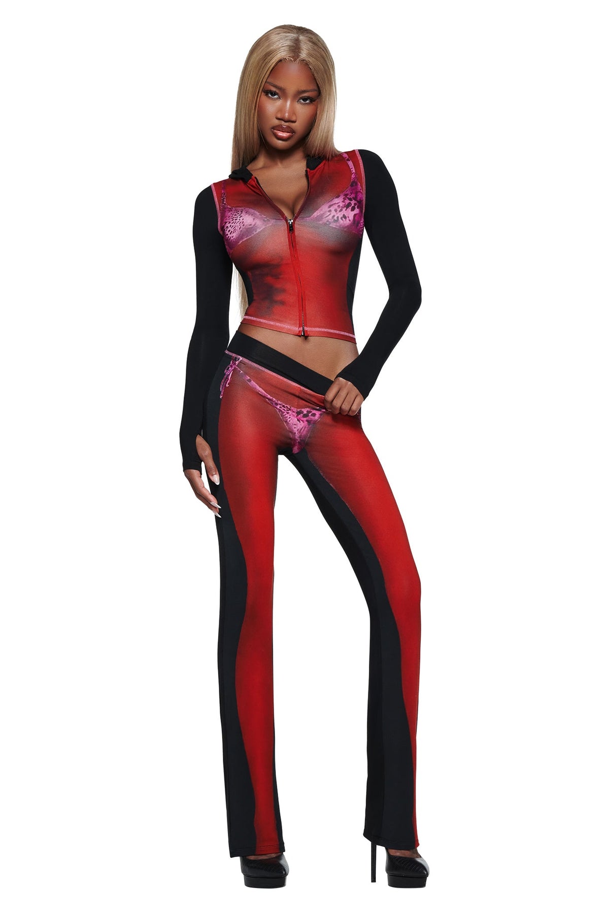 A woman models the T-REX SPRAY BODY BLARE HOODIE - BLACK by I.AM.GIA, featuring sheer red and black long sleeves over an airbrushed bikini print, styled with straight blonde hair and black heels against a white background.