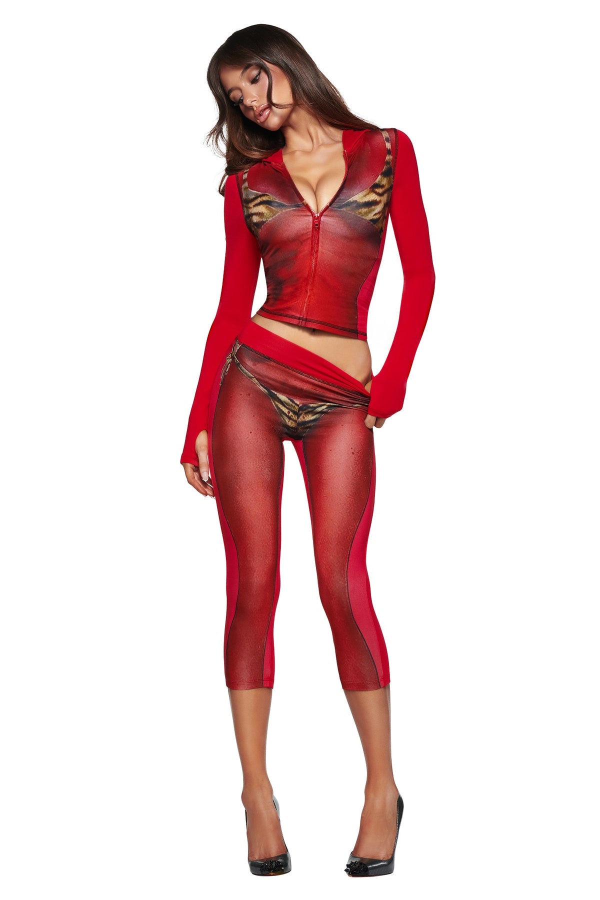 A woman poses in the T-REX SPRAY BODY BLARE HOODIE - RED by I.AM.GIA, styled with sheer leggings, tiger-print accents, and high heels against a white background, highlighting its bold airbrushed bikini body print.