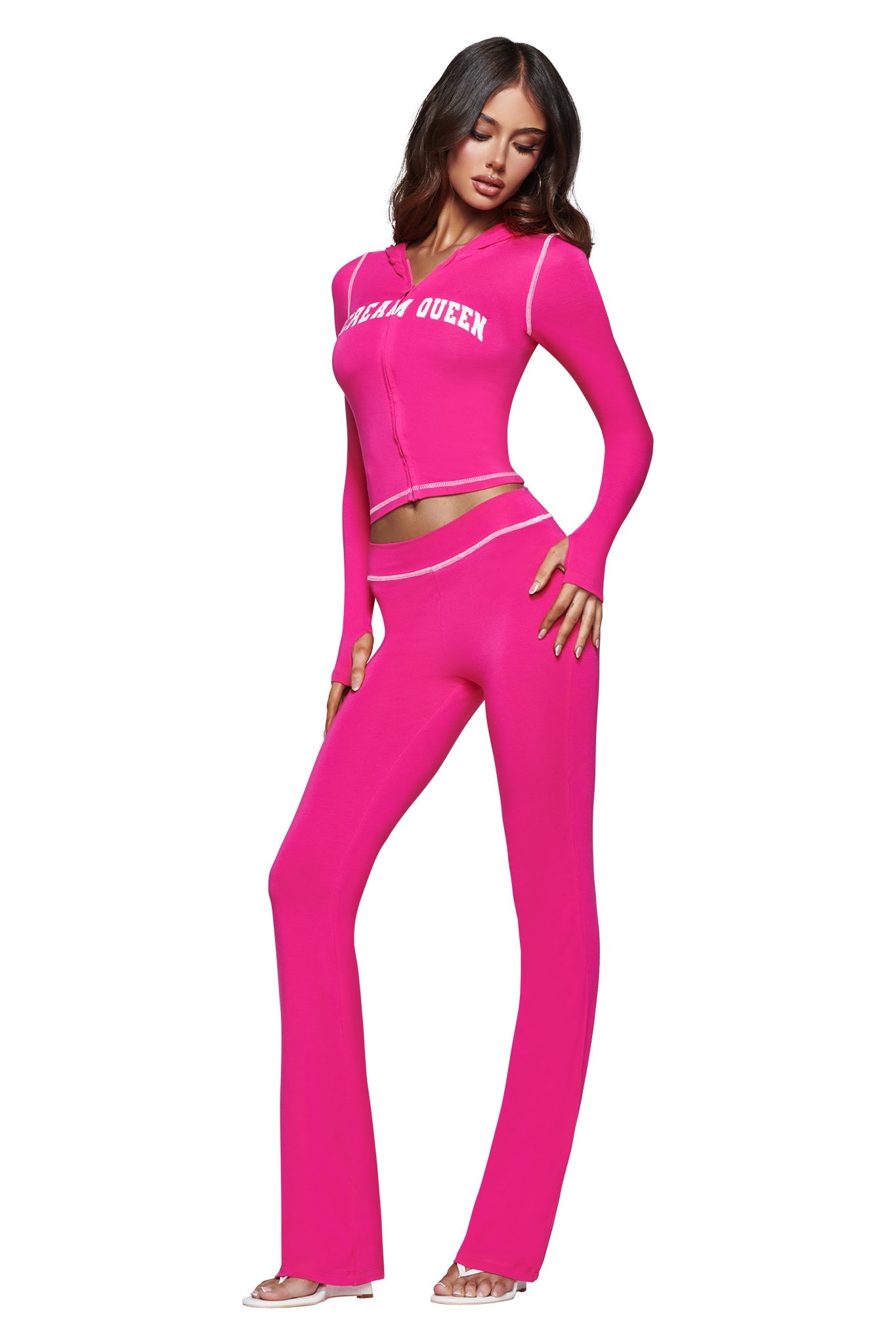 A woman wears the I.AM.GIA BLARE HOODIE in Hot Pink Scream Queen, a bright pink matching set with long sleeves and flared pants made from soft bamboo fabric. The top showcases a bold “GLAM QUEEN” graphic in white, echoing the signature Scream Queen style. She stands against a white background with one hand on her hip.