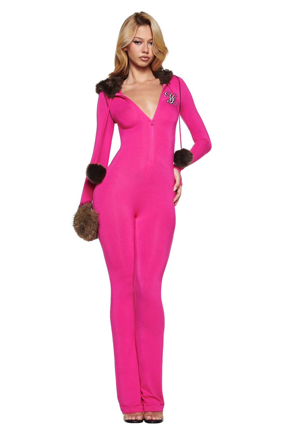 A woman wears a hot pink I.AM.GIA YVL BLARE FUR LINED JUMPSUIT with a deep-v zippered neckline, brown faux-fur trim on the hood and cuffs, and a small embroidered logo on the chest.
