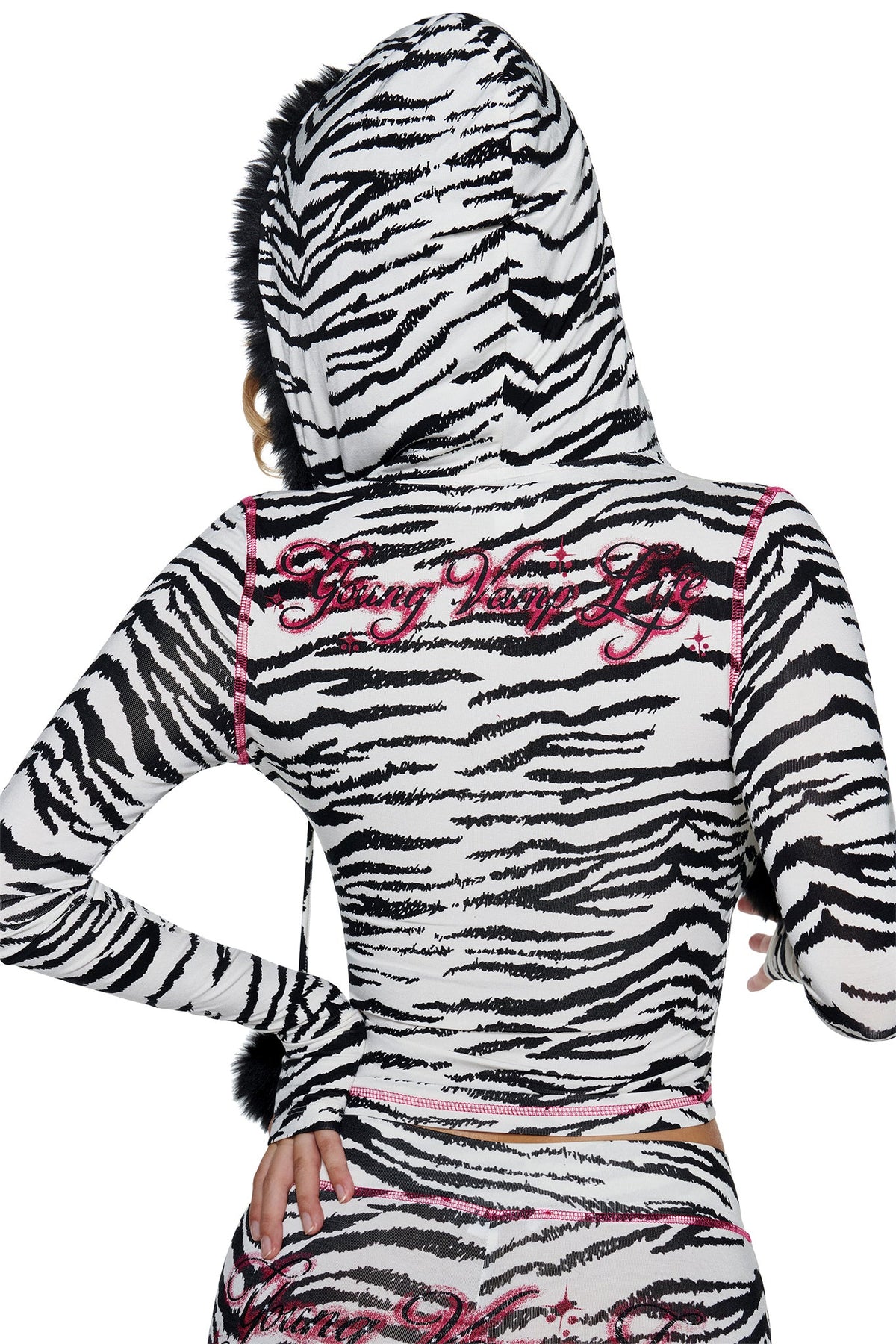 Back view of a white, zebra-print I.AM.GIA YVL BLARE FUR LINED HOODIE - ZEBRA with pink stitching, featuring a faux fur lining and the phrase “Young Vamp Life” embroidered in pink on the upper back.