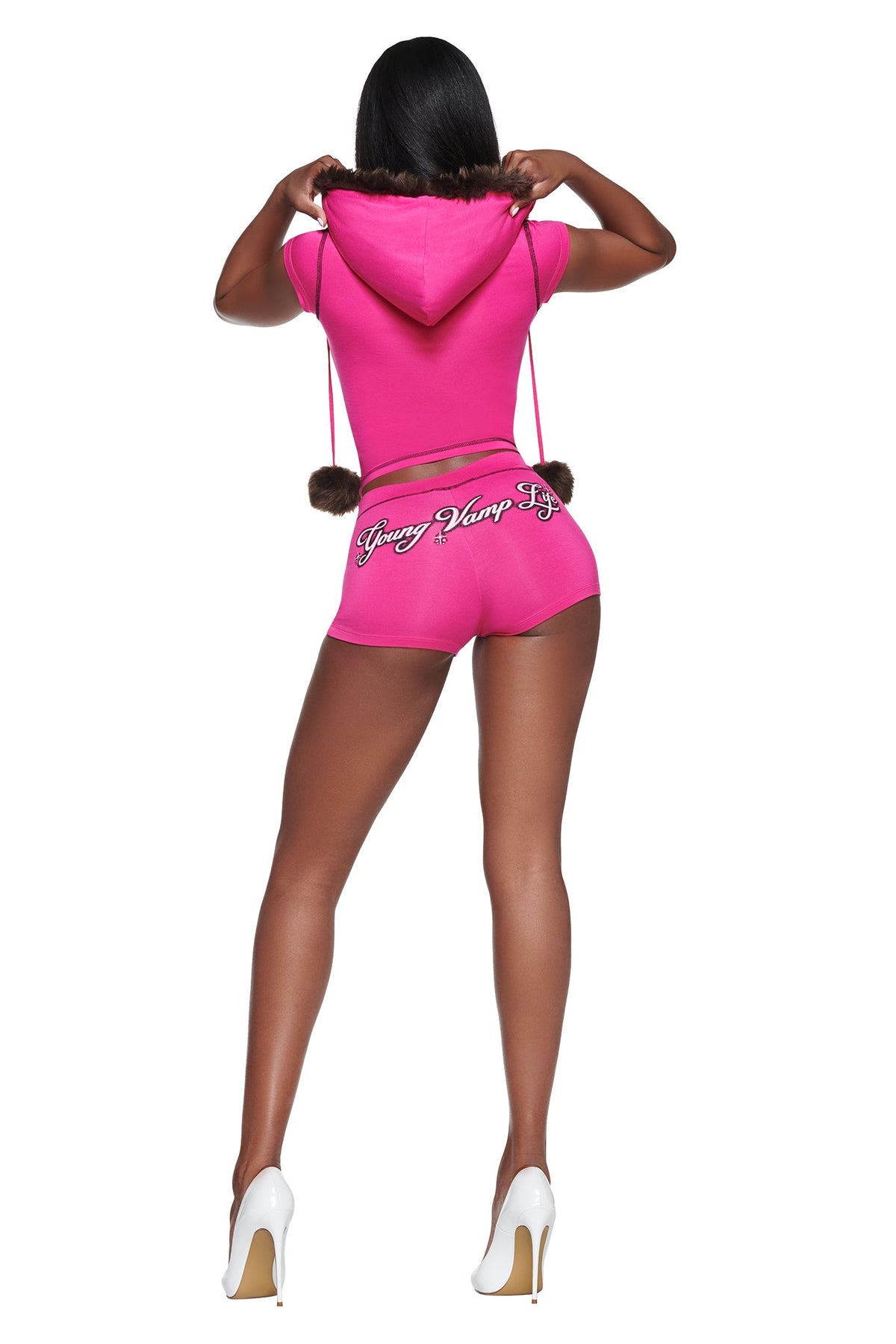 A person wearing a bright pink, faux fur-lined YVL BLARE FUR LINED CAP SLEEVE HOODIE with cap sleeves and matching shorts that feature the text “Young Vamp Life” on the back.