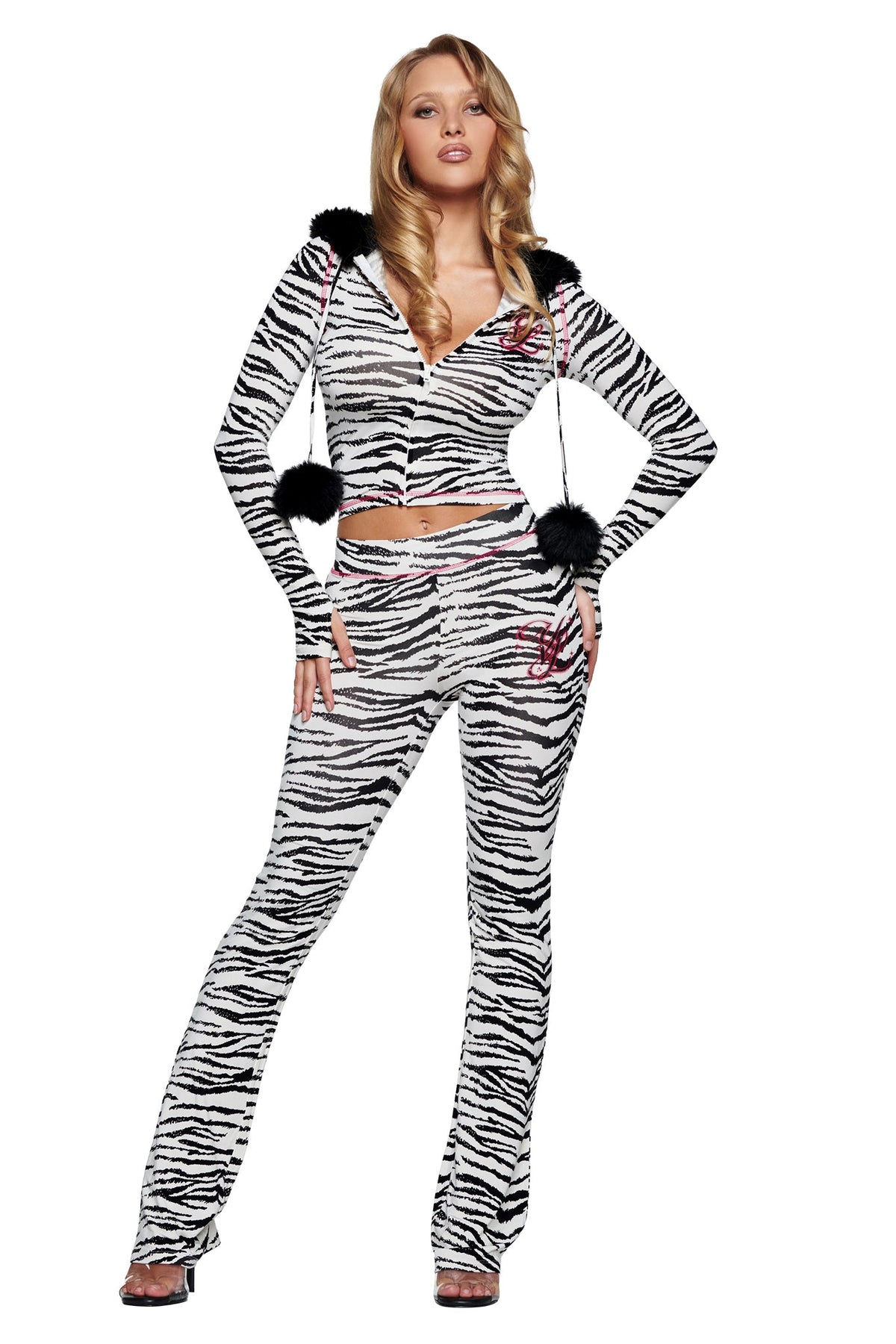 A person wearing a zebra-print zip-up hoodie with black fur pom-poms and matching YVL BLARE TRACKPANT - ZEBRA flared-leg pants.
