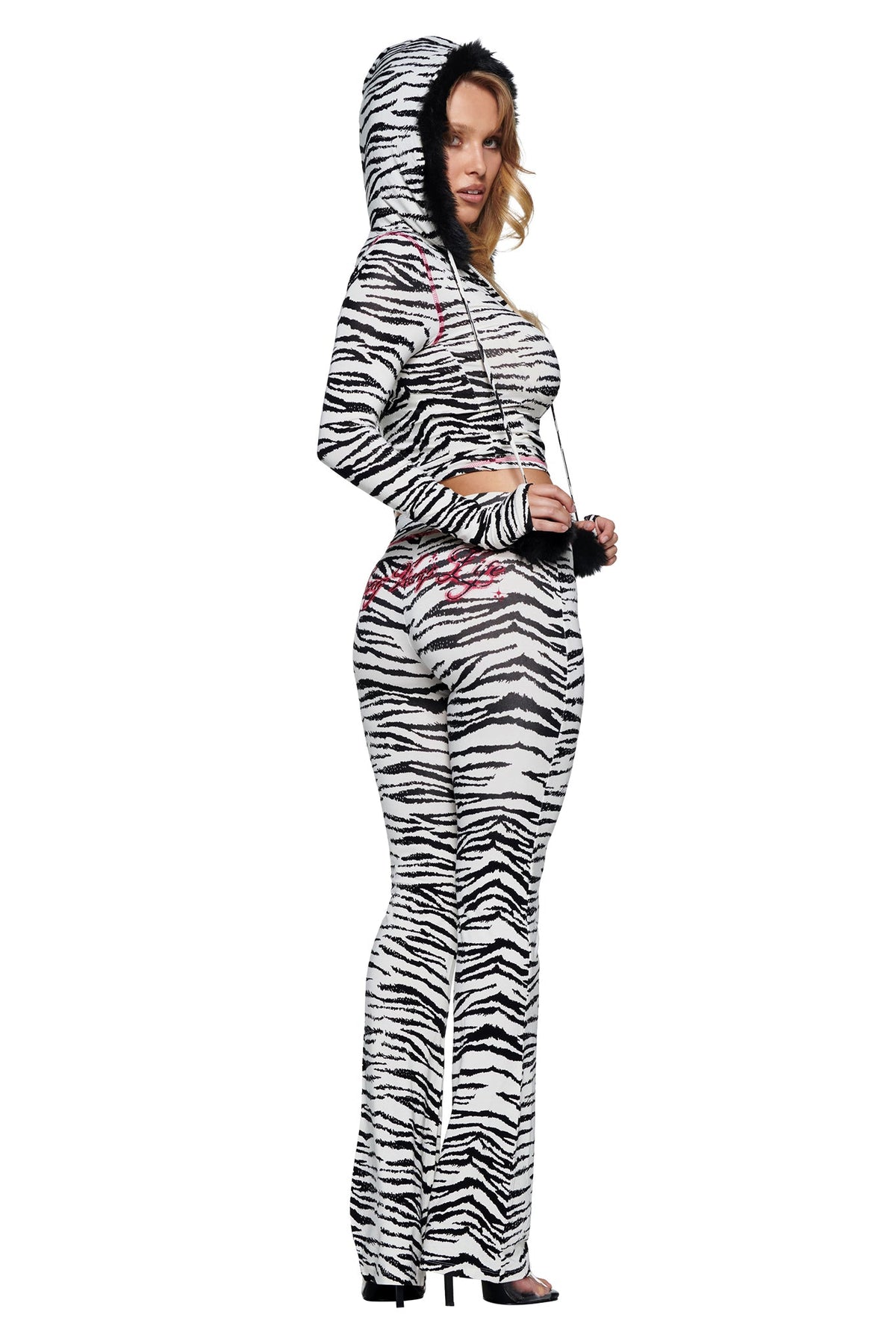 A person wearing a zebra-print hooded long-sleeve crop top and matching YVL BLARE TRACKPANT - ZEBRA with pink embroidered lettering on the back.
