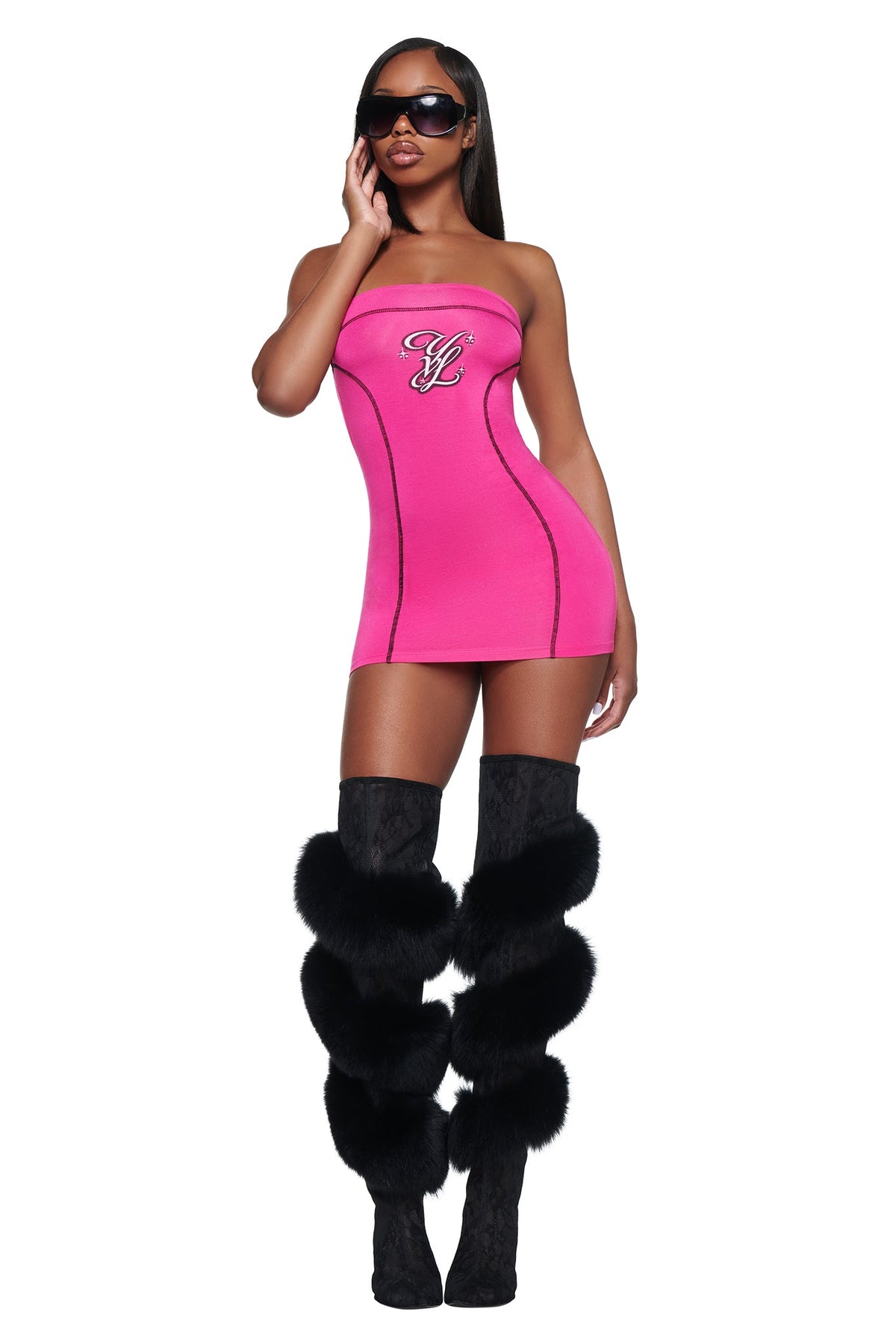 A woman wearing a hot pink I.AM.GIA YVL BLARE TUBE MINI DRESS and black over-the-knee boots with fur trim.