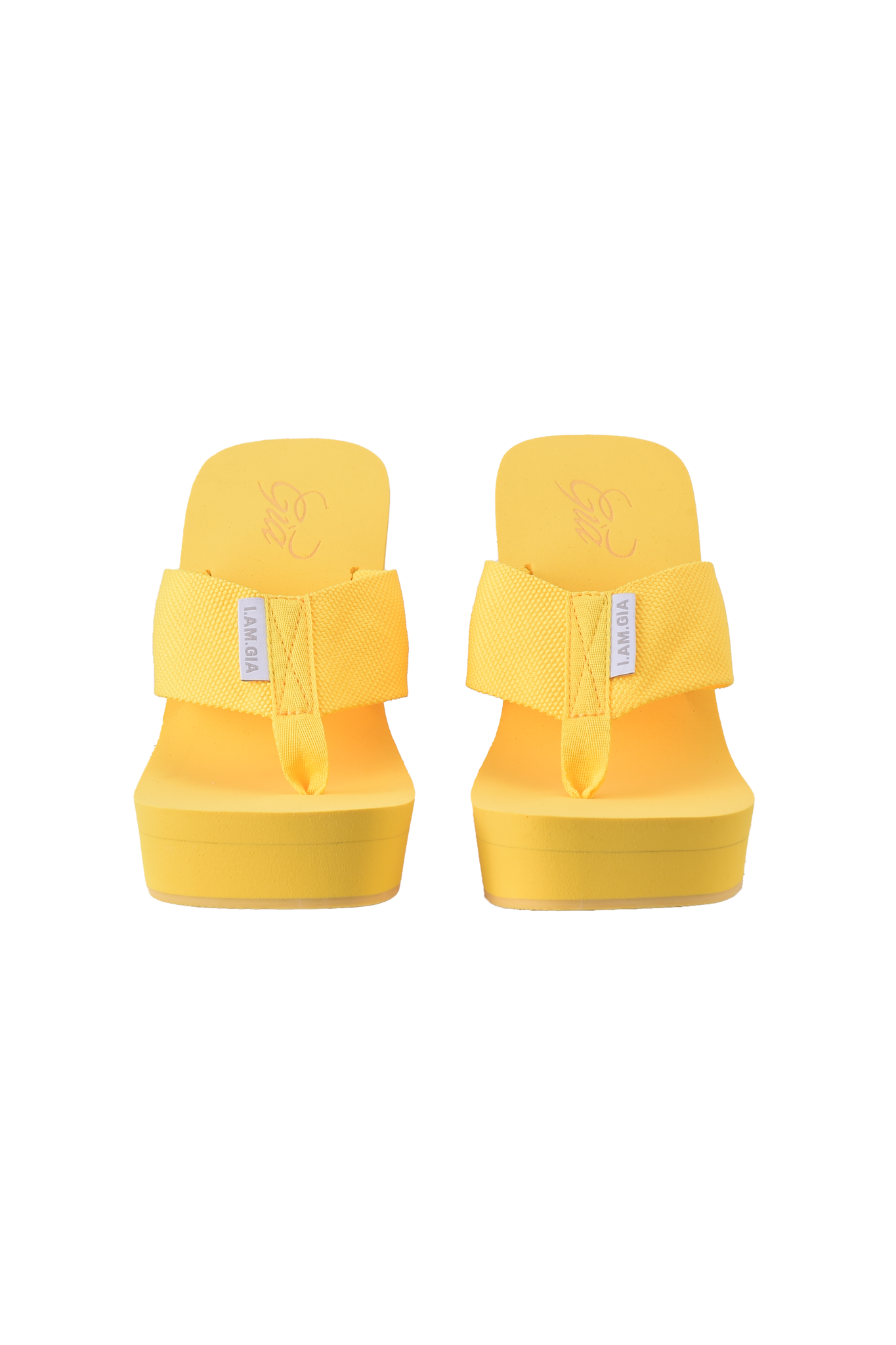 The SHELBY FLIP FLOP - YELLOW by I.AM.GIA features vibrant yellow wedge soles and wide fabric straps with small white labels, shown from the front on a neutral background, capturing the brand’s bold signature style.